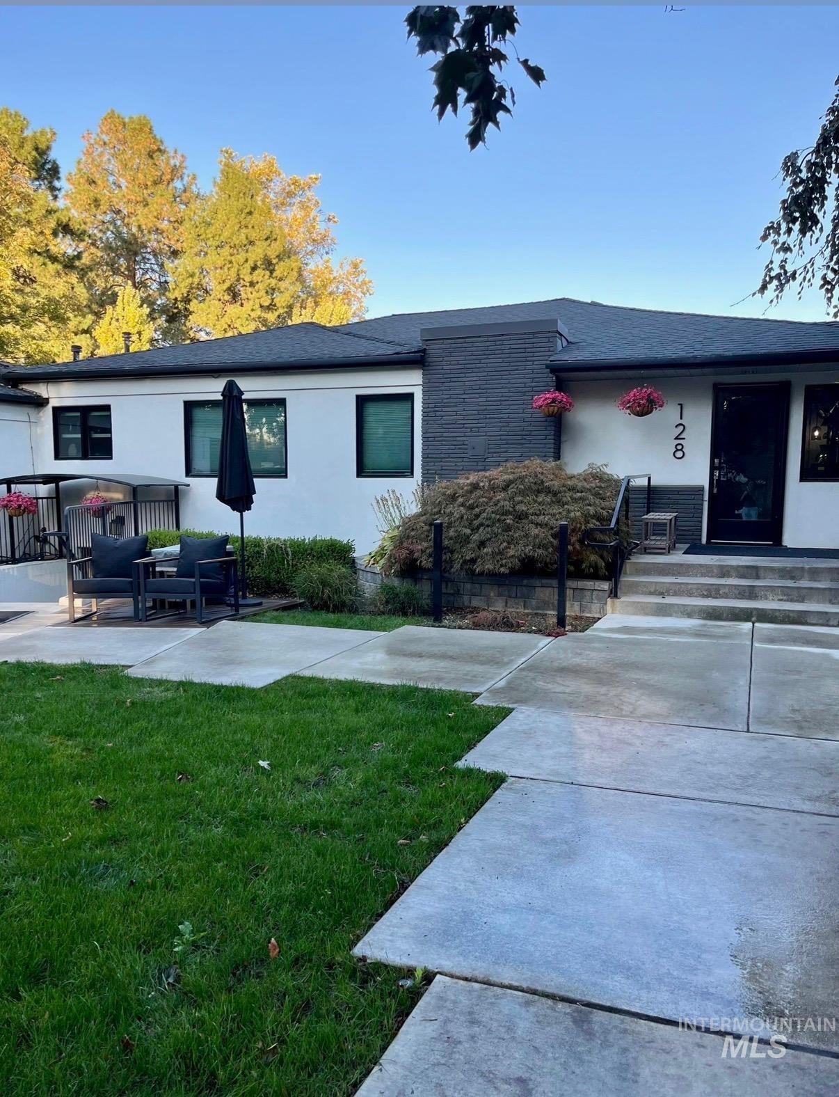 View of front of home with a shingled roof, brick siding, a front yard, and stucco siding