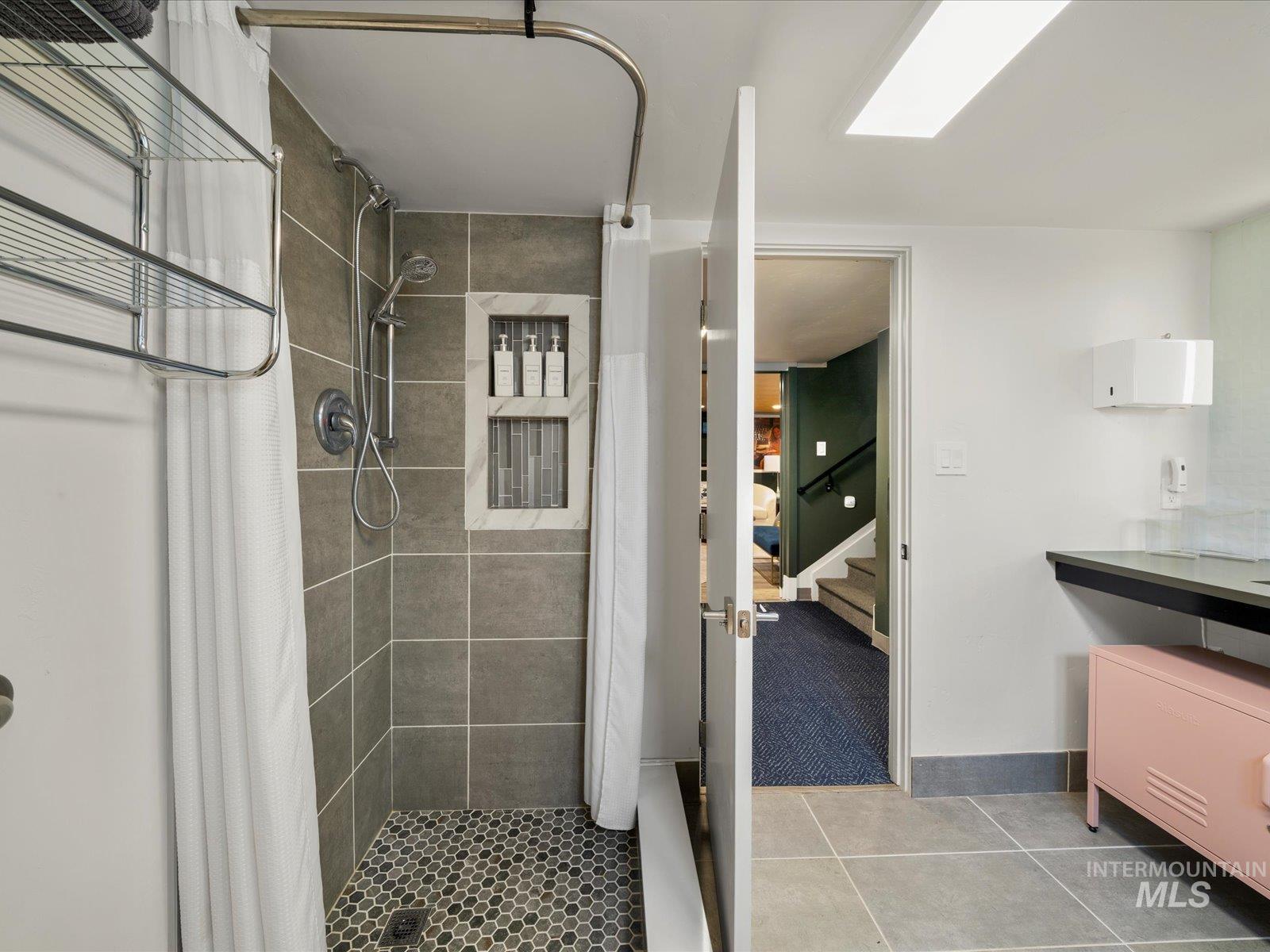Full bathroom featuring a shower stall, light tile patterned flooring, and vanity