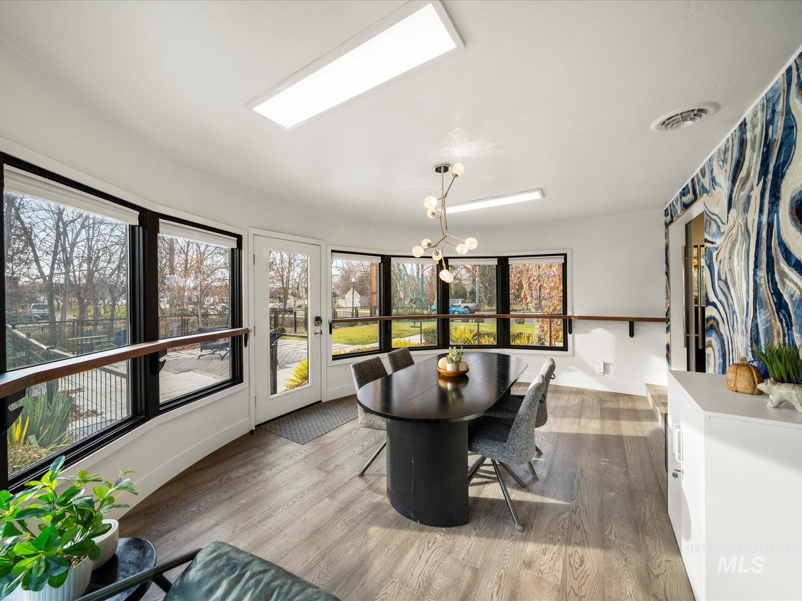 Sunroom / solarium featuring wood finished floors and a chandelier