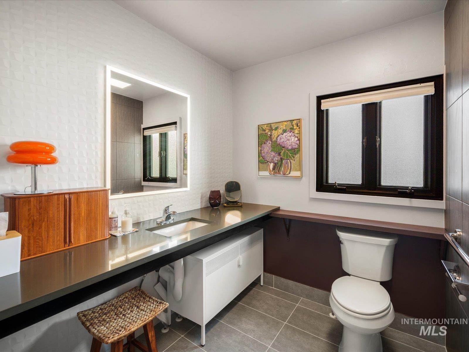 Half bathroom featuring vanity, light tile patterned flooring, and decorative backsplash