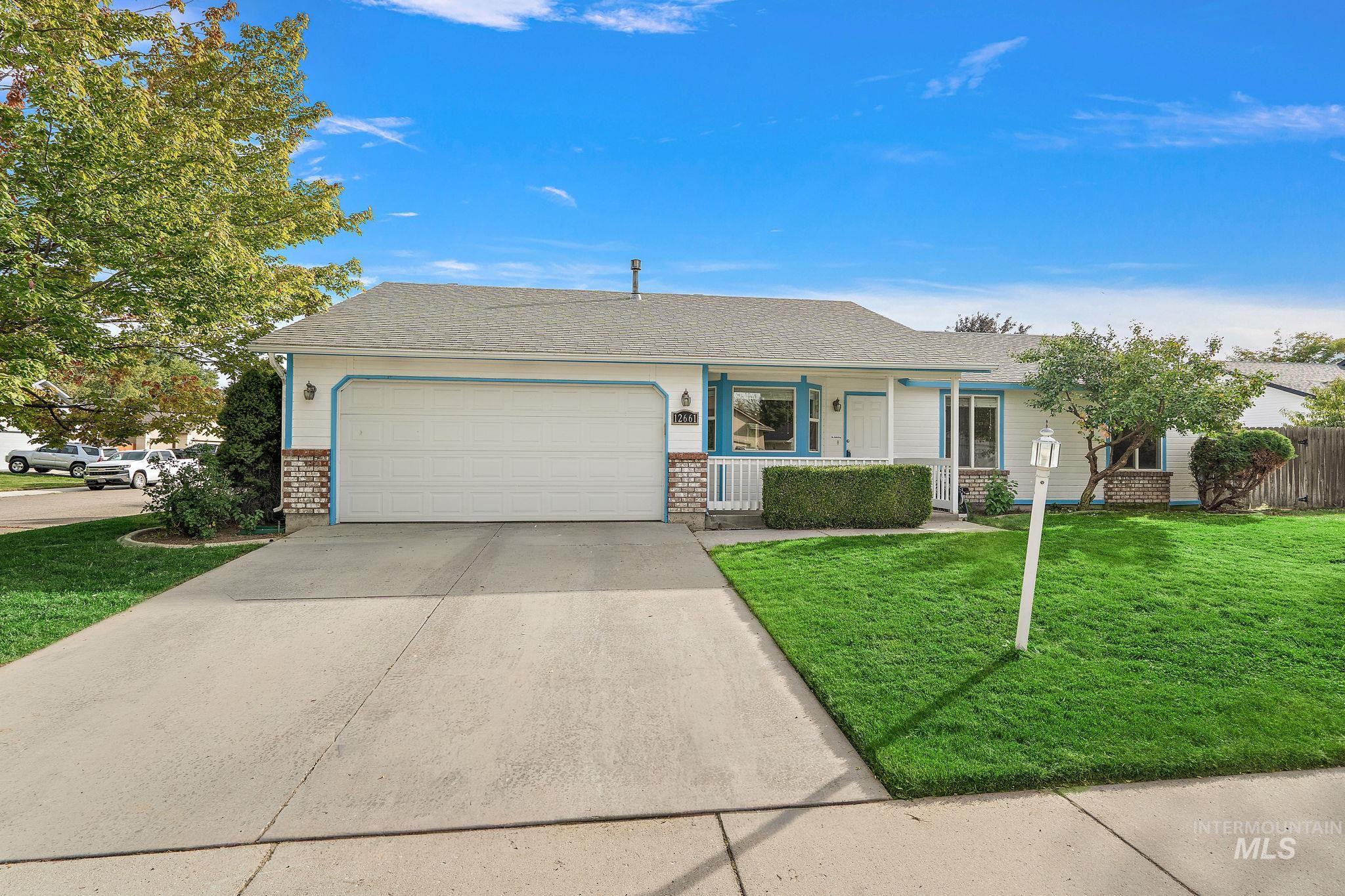 Ranch-style home with a front yard, driveway, an attached garage, brick siding, and a shingled roof
