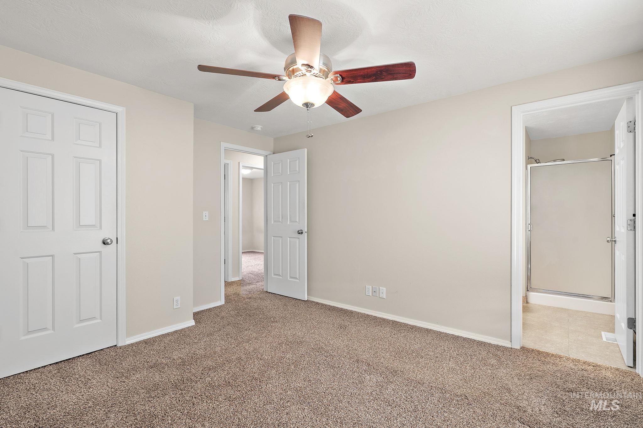 Unfurnished bedroom with light carpet, ceiling fan, and ensuite bathroom