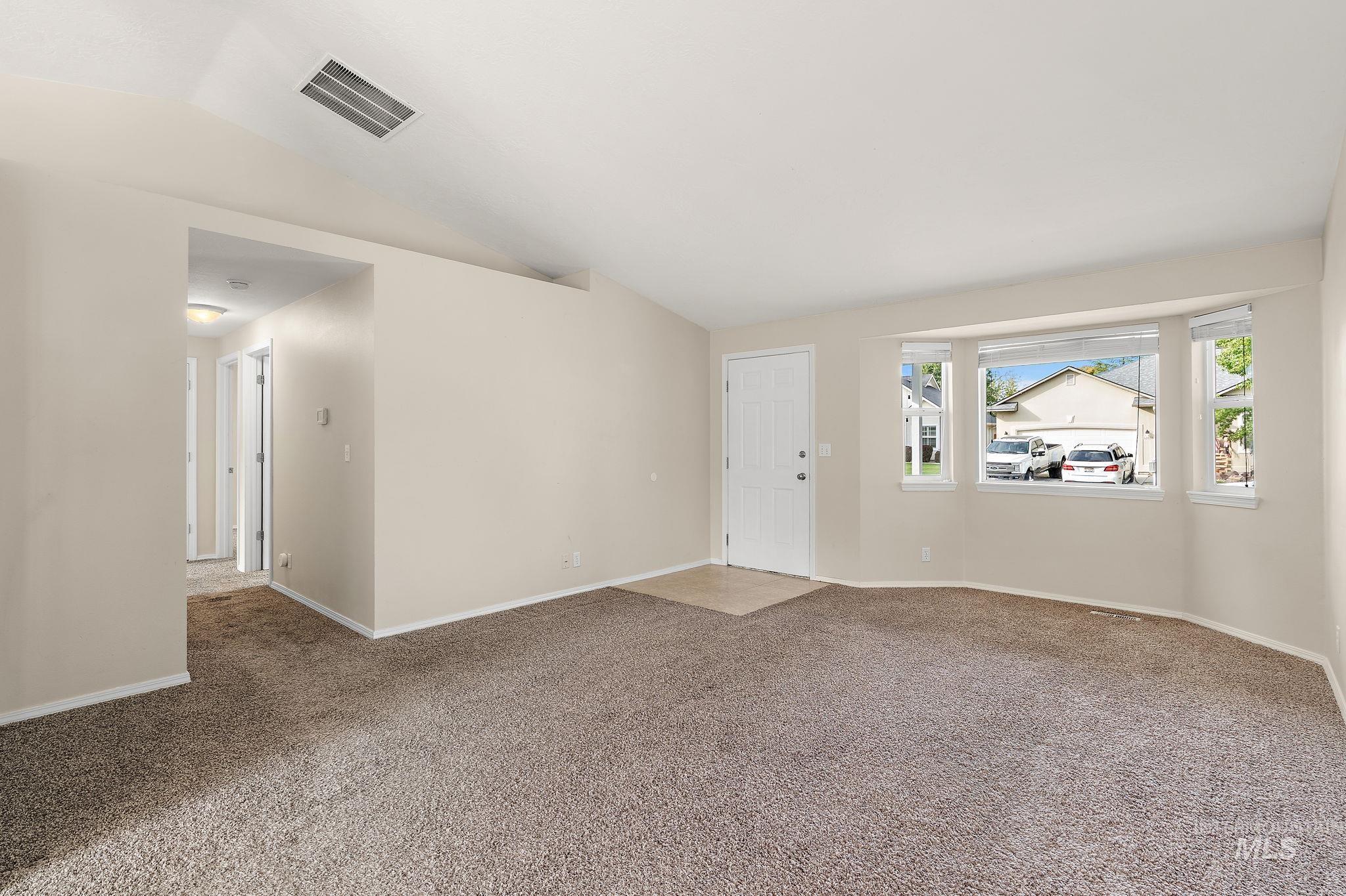 Carpeted spare room with lofted ceiling and baseboards