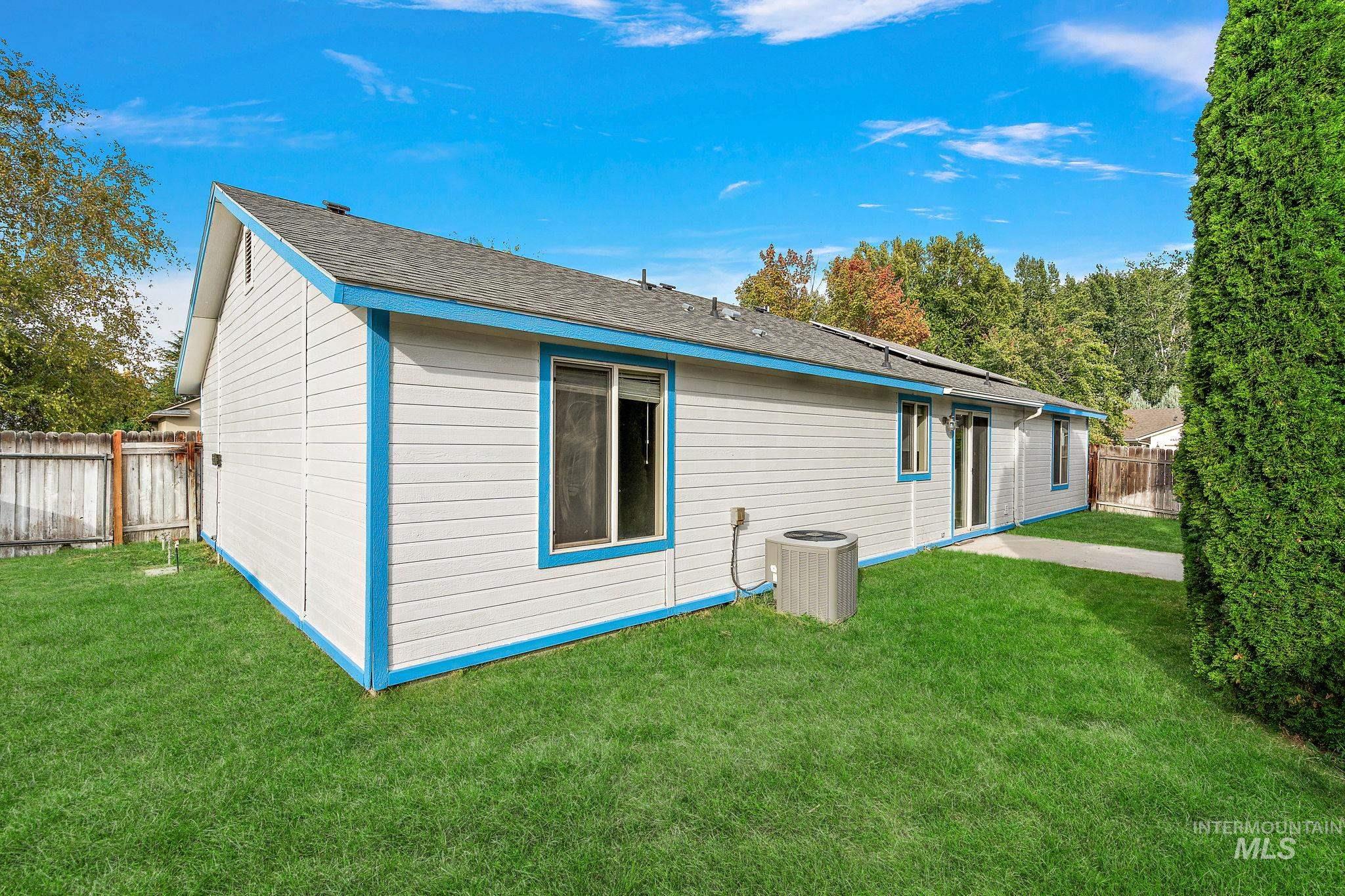 Rear view of house with a fenced backyard, a shingled roof, and a patio area