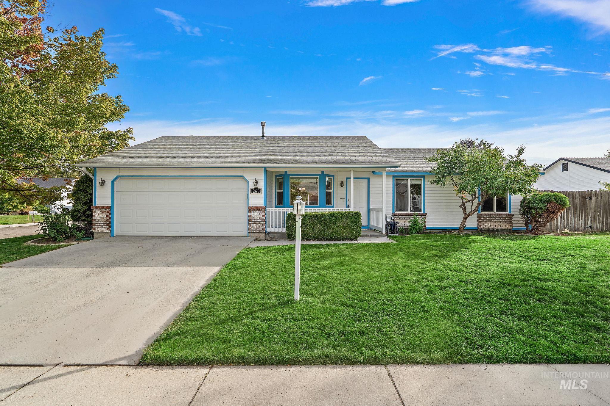 Single story home featuring driveway, a shingled roof, a porch, brick siding, and an attached garage