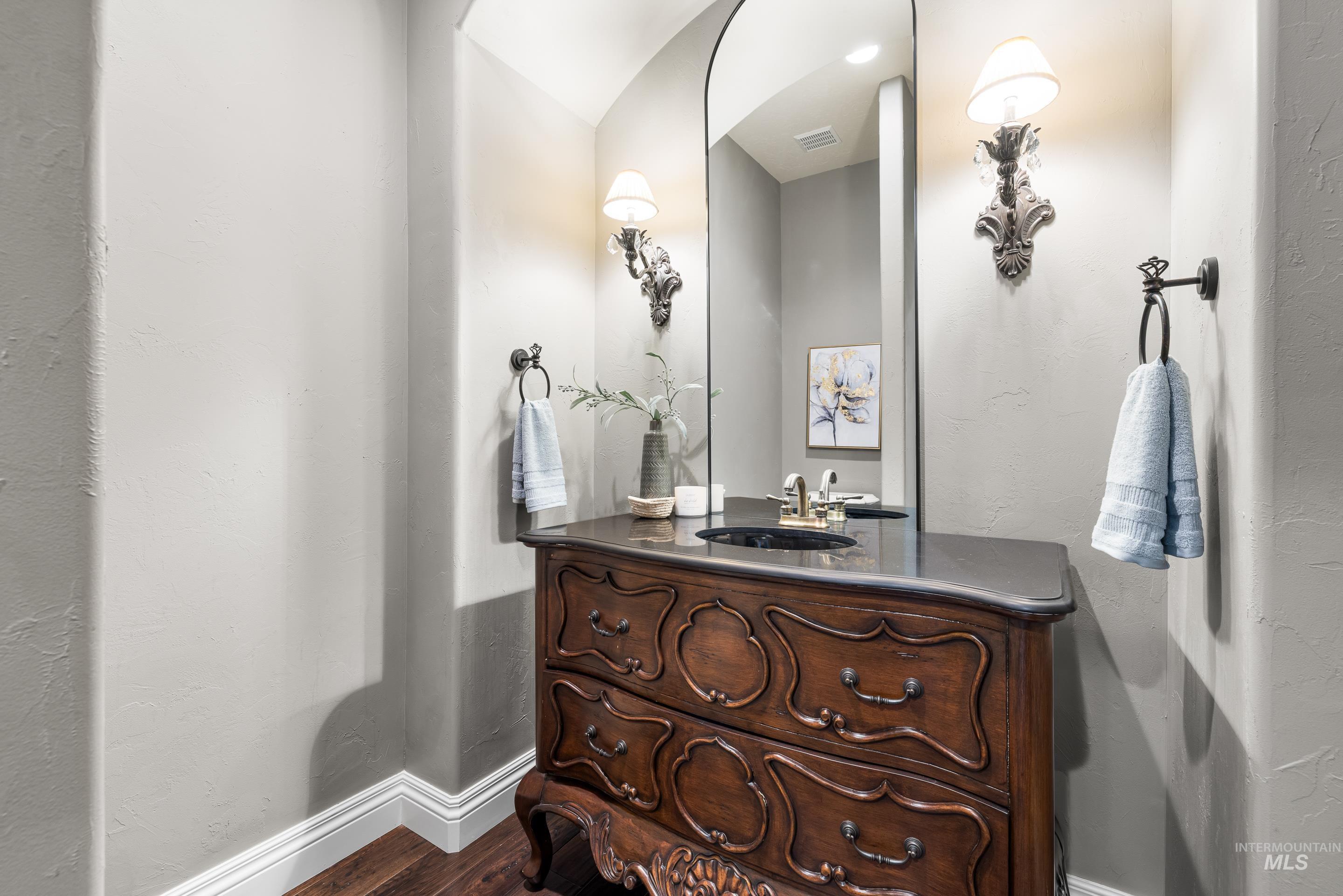 Half bathroom with a textured wall, vanity, and wood finished floors