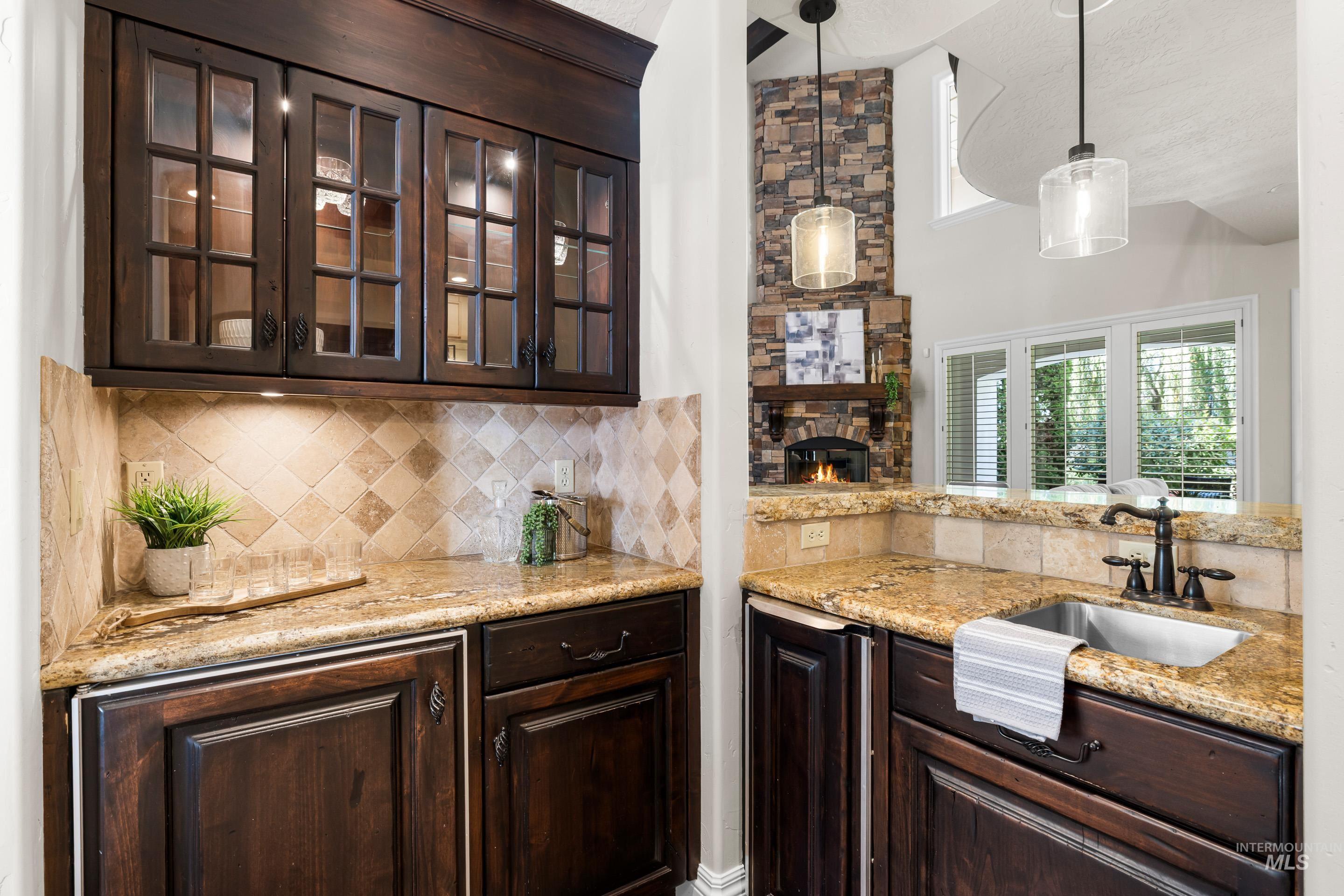 Bar area featuring healthy amount of natural light, hanging light fixtures, decorative backsplash, a textured ceiling, and a high ceiling