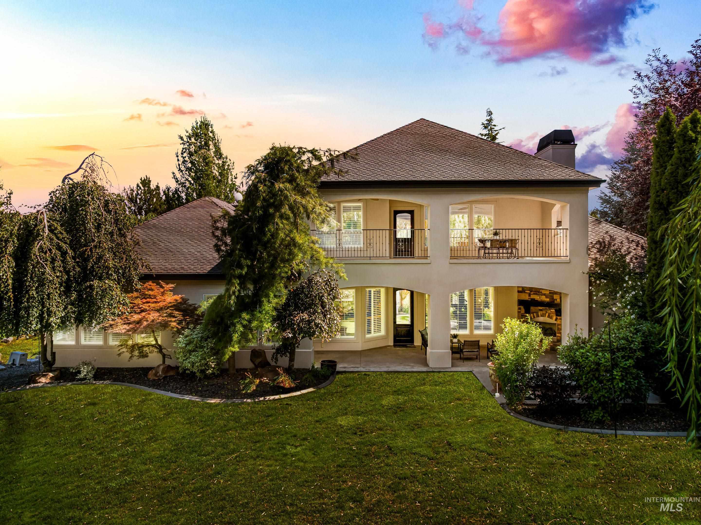 Back of property with a patio area, a chimney, stucco siding, a balcony, and a yard
