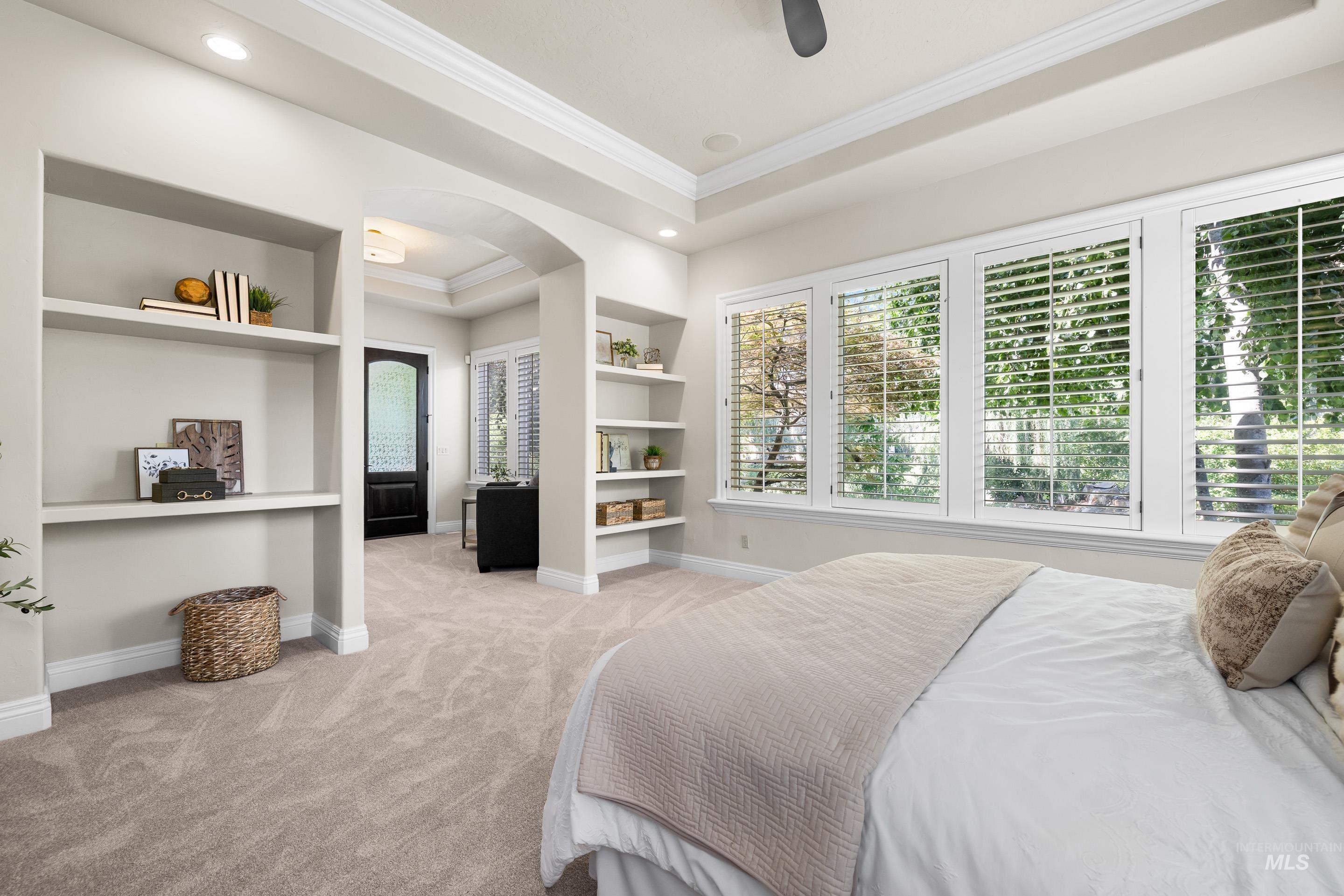 Bedroom featuring multiple windows, arched walkways, ornamental molding, light carpet, and recessed lighting