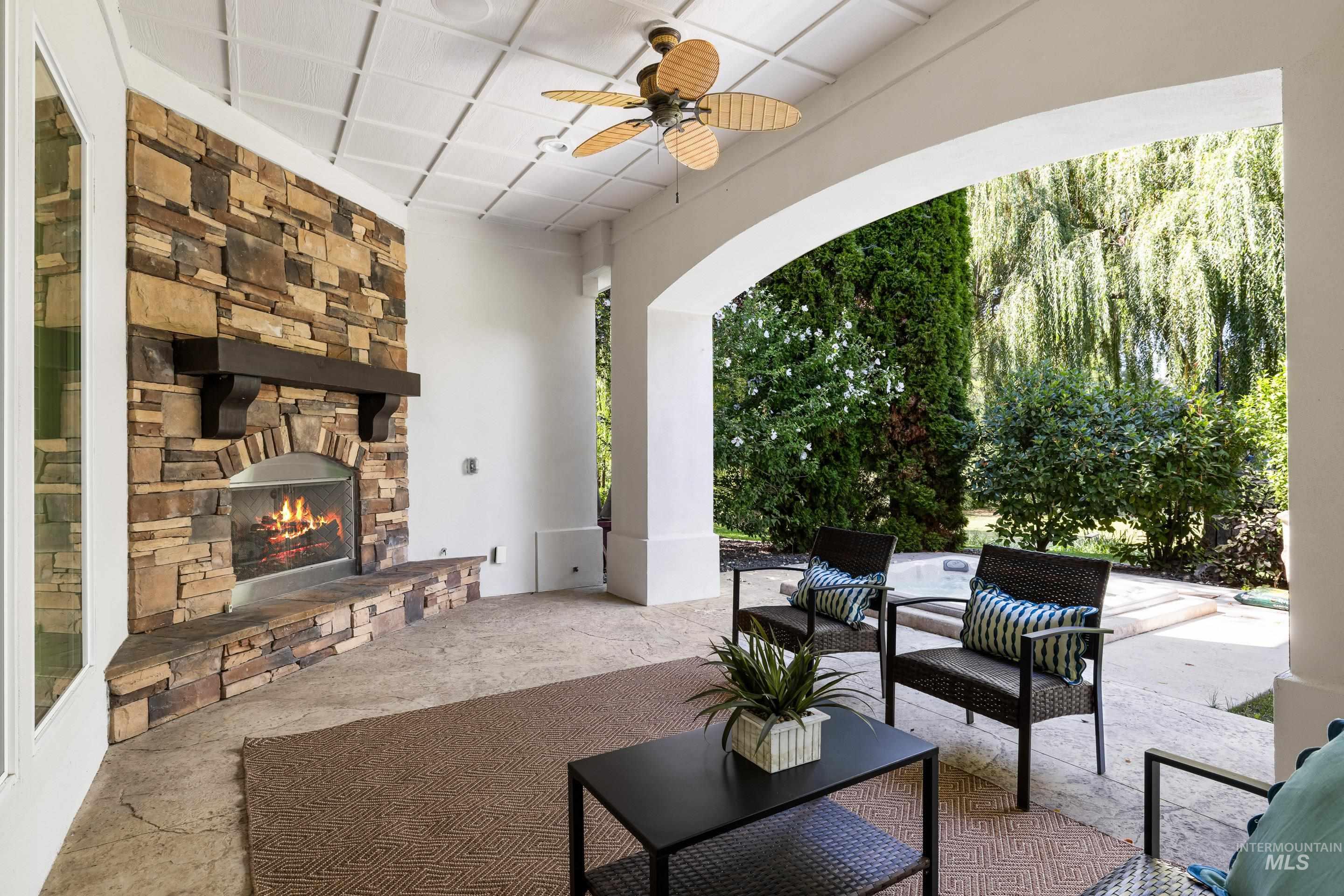View of patio featuring an outdoor stone fireplace and a ceiling fan