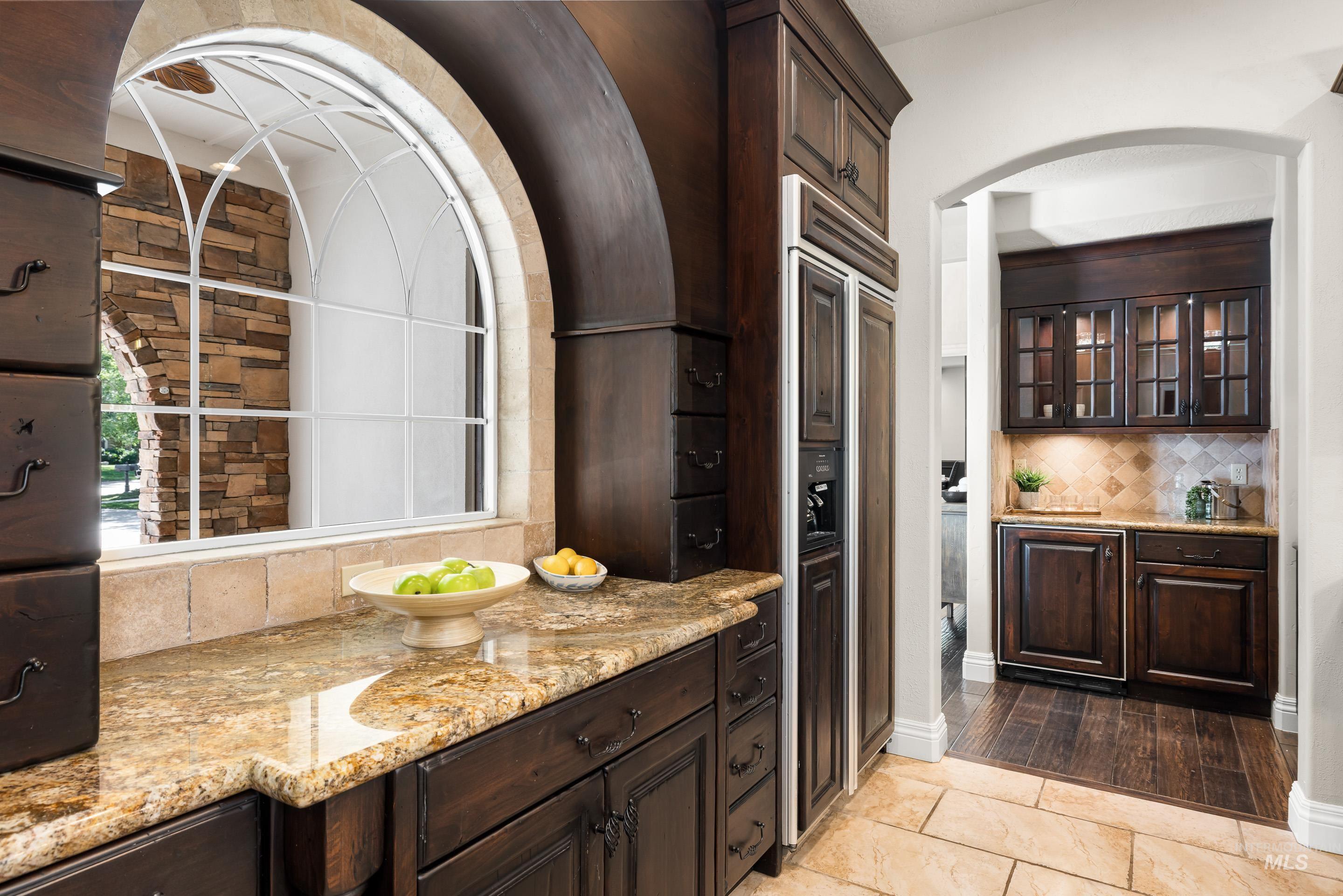 Bar with arched walkways, decorative backsplash, and paneled built in refrigerator