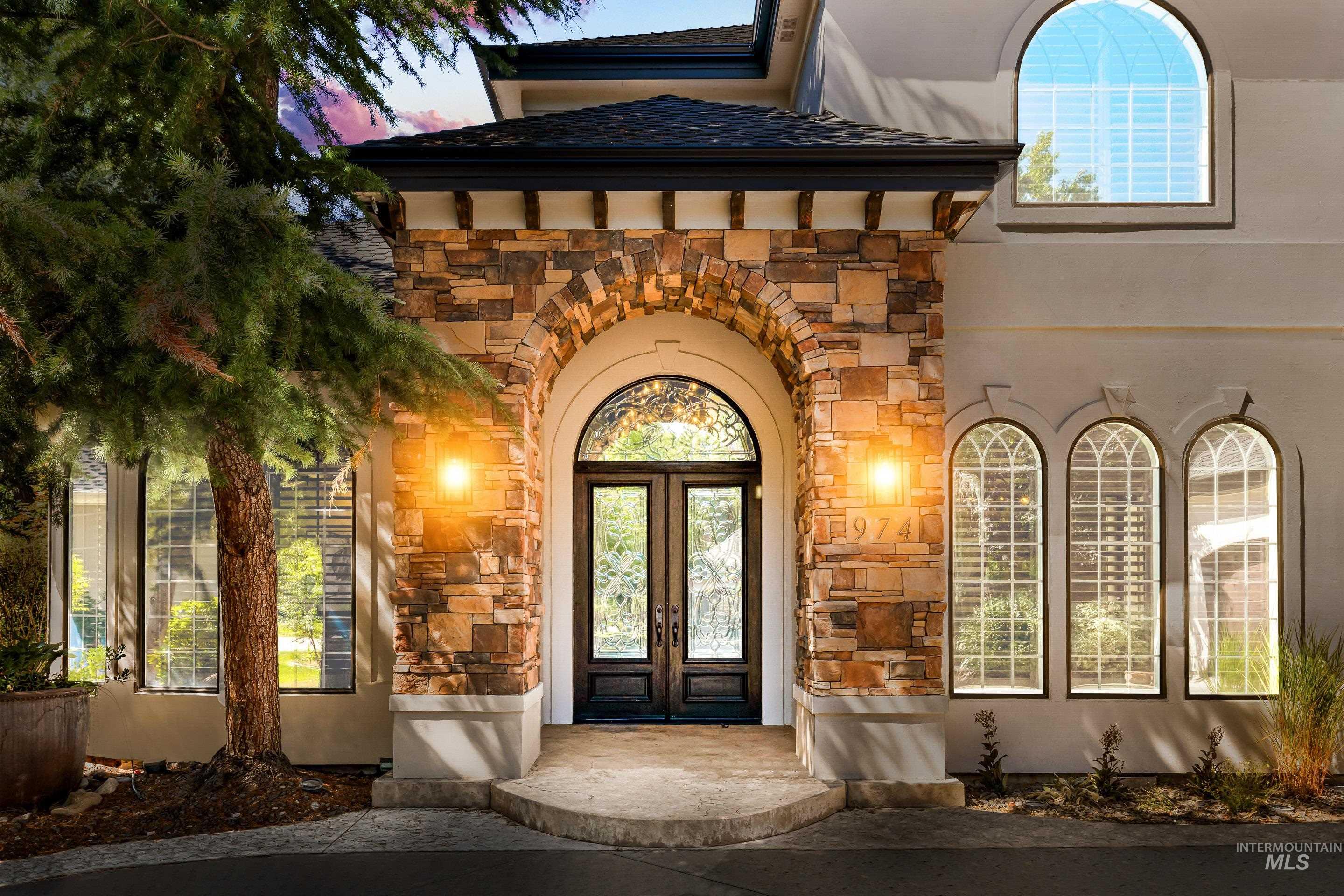 Entrance to property featuring stone siding, french doors, and stucco siding