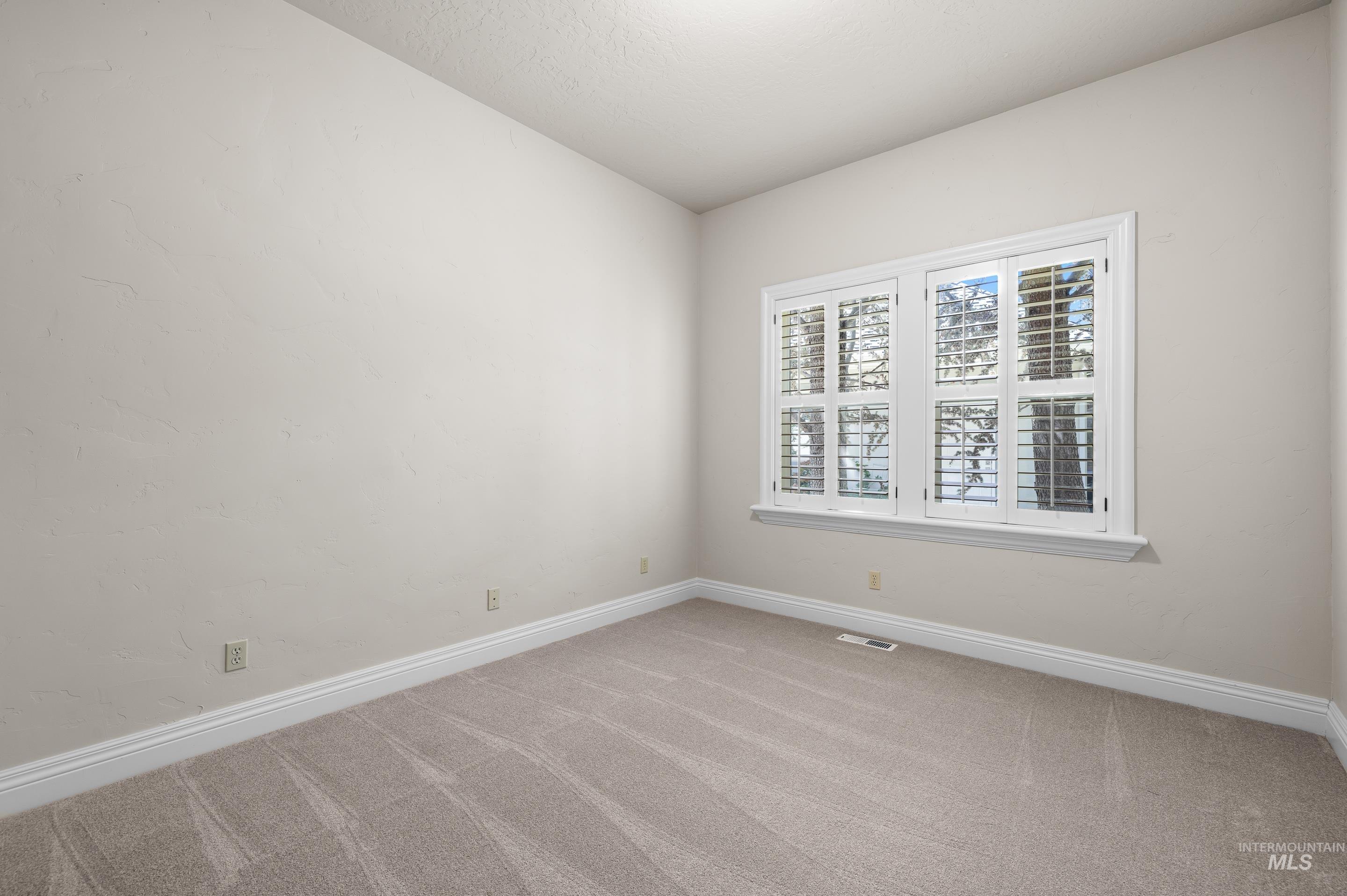 Carpeted empty room featuring baseboards