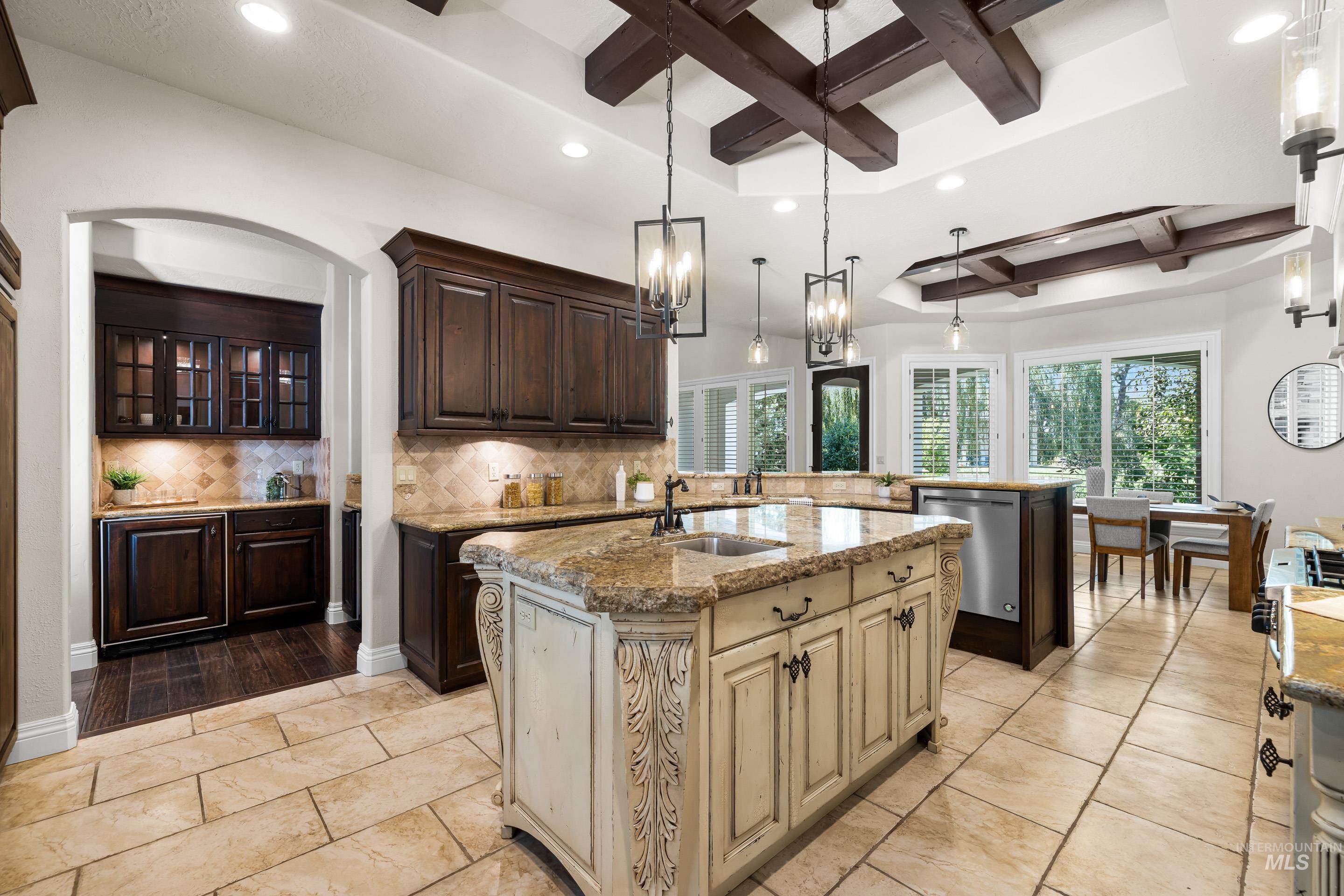 Kitchen featuring recessed lighting, coffered ceiling, beamed ceiling, a kitchen island with sink, and dark brown cabinetry