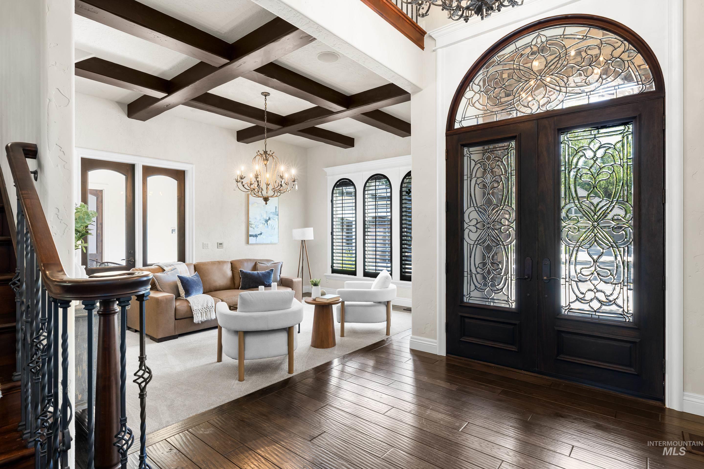 Foyer entrance featuring french doors, beam ceiling, dark wood-type flooring, healthy amount of natural light, and a chandelier