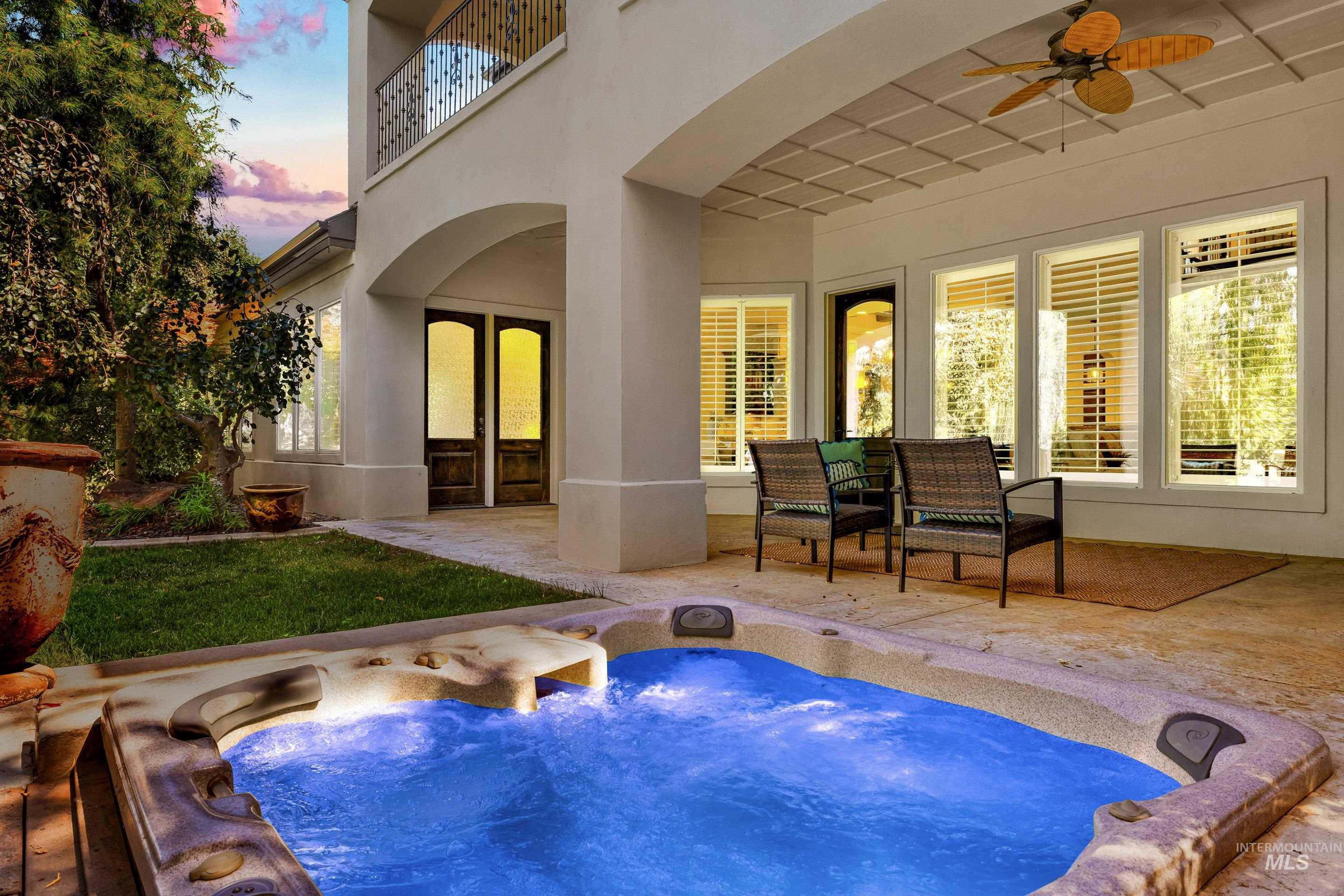 Pool at dusk with a patio area, a ceiling fan, and a balcony