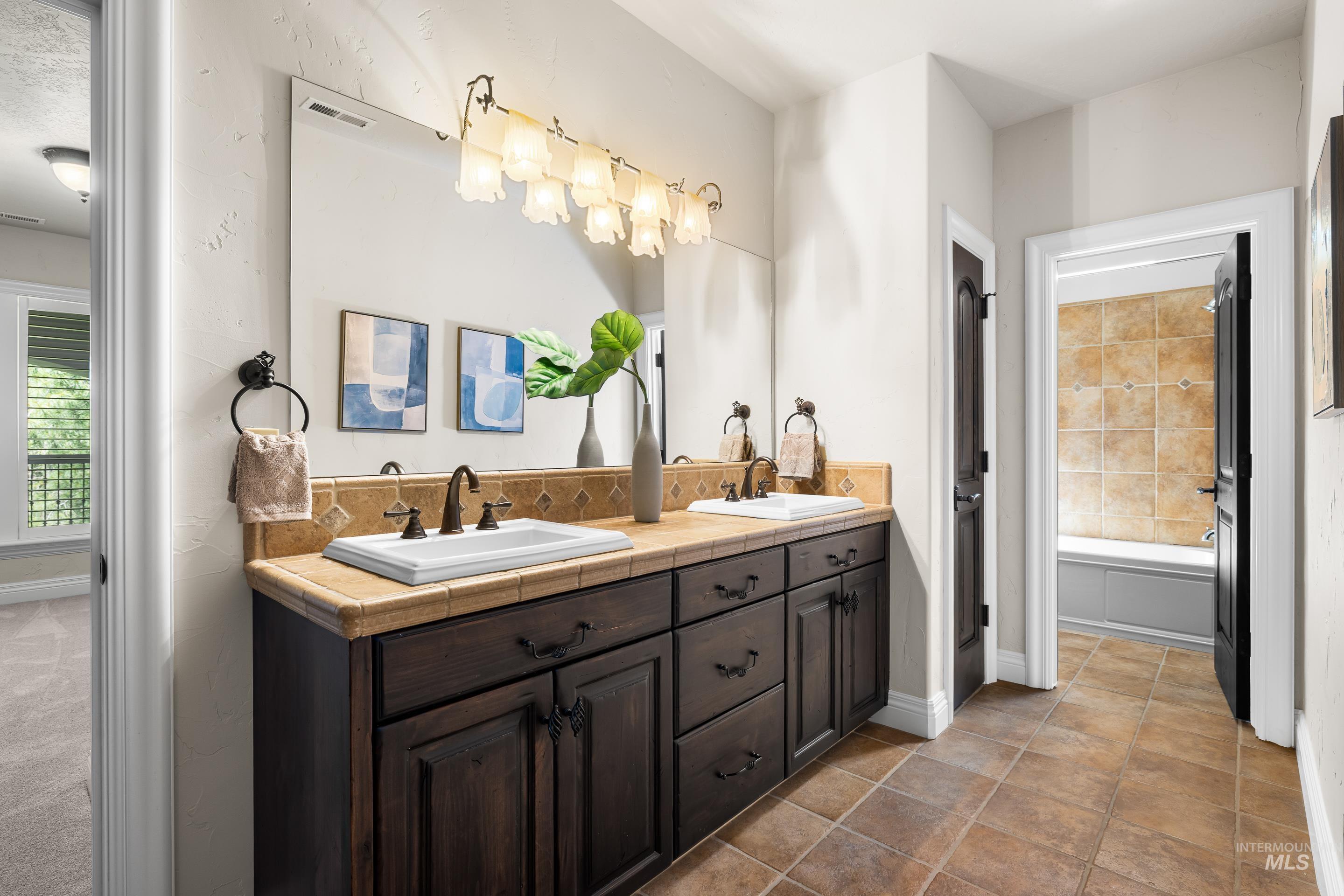 Full bath featuring double vanity and tile patterned floors