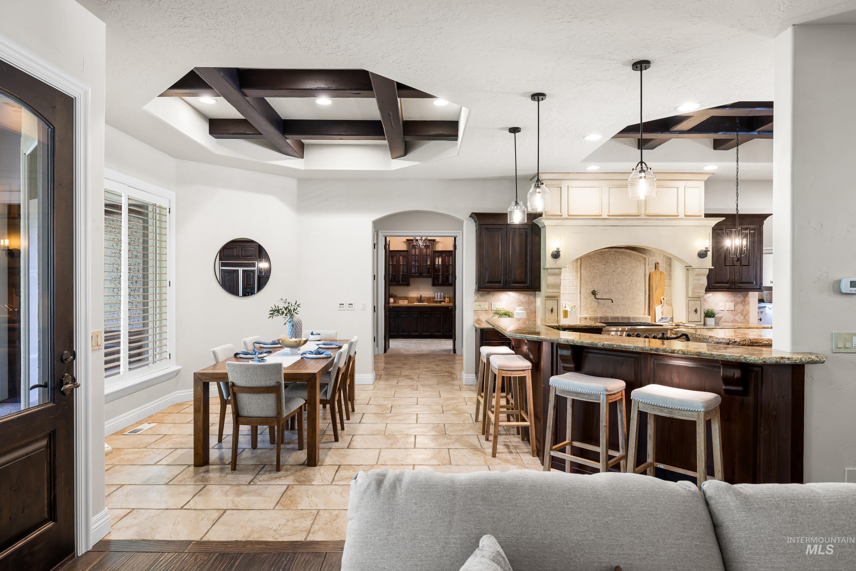 Dining area with coffered ceiling, arched walkways, beam ceiling, recessed lighting, and light tile patterned floors