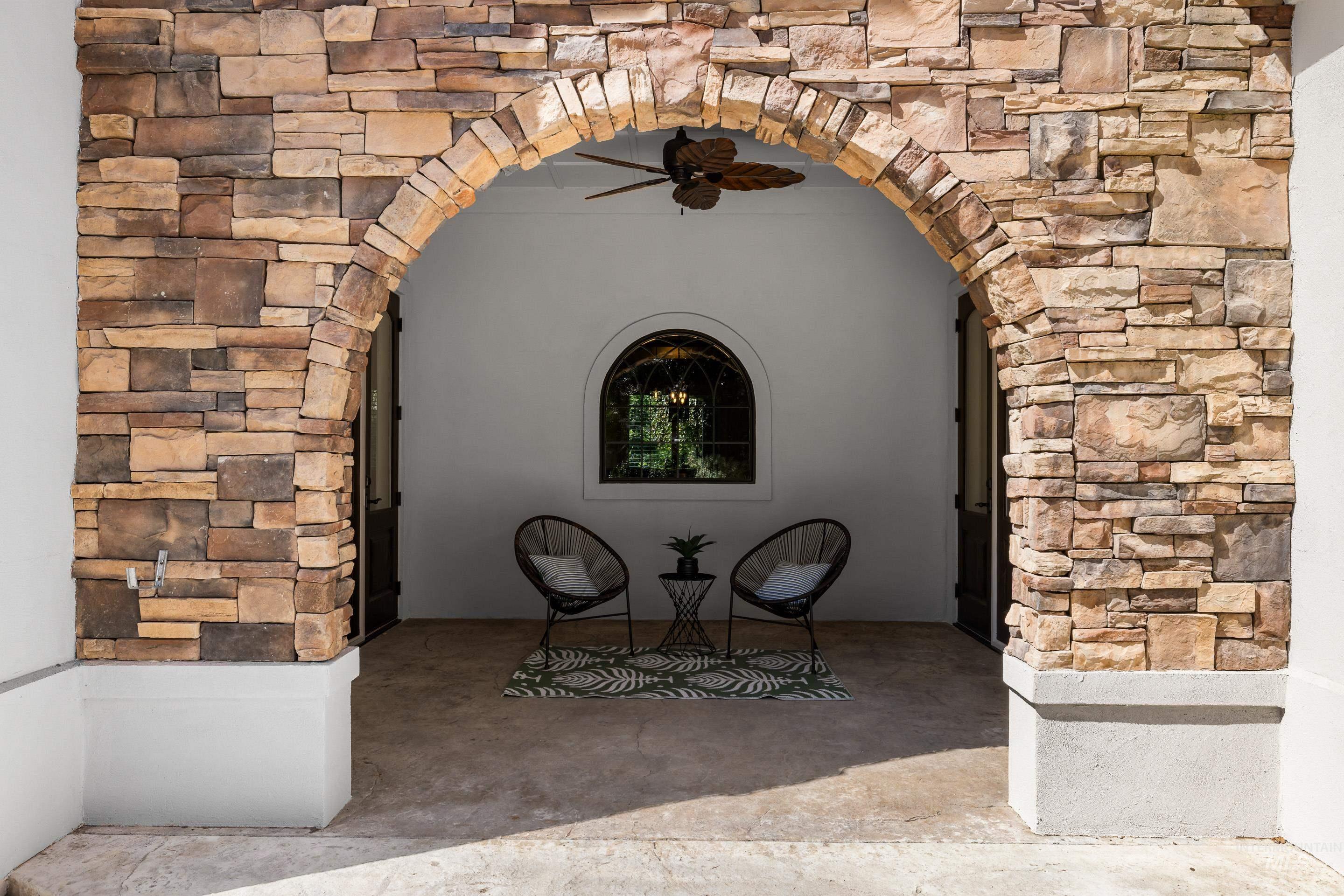 Entrance to property featuring stone siding, stucco siding, and a patio