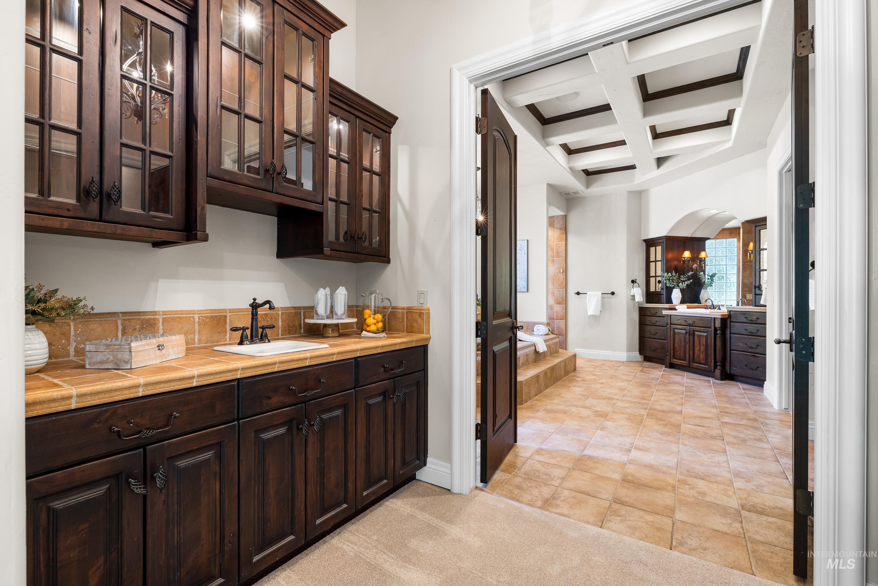 Indoor wet bar with coffered ceiling, beamed ceiling, and arched walkways