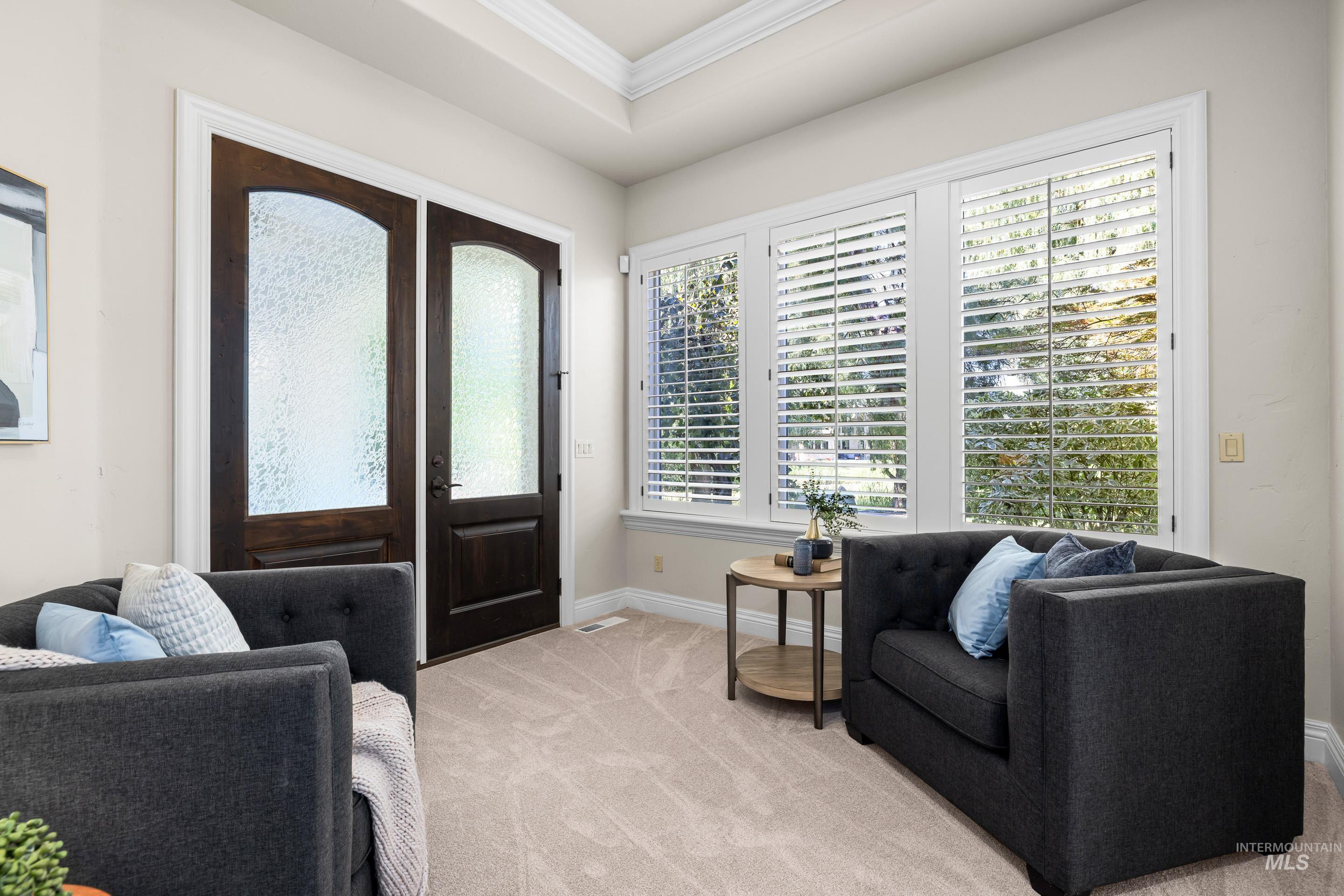 Foyer entrance featuring crown molding and light carpet