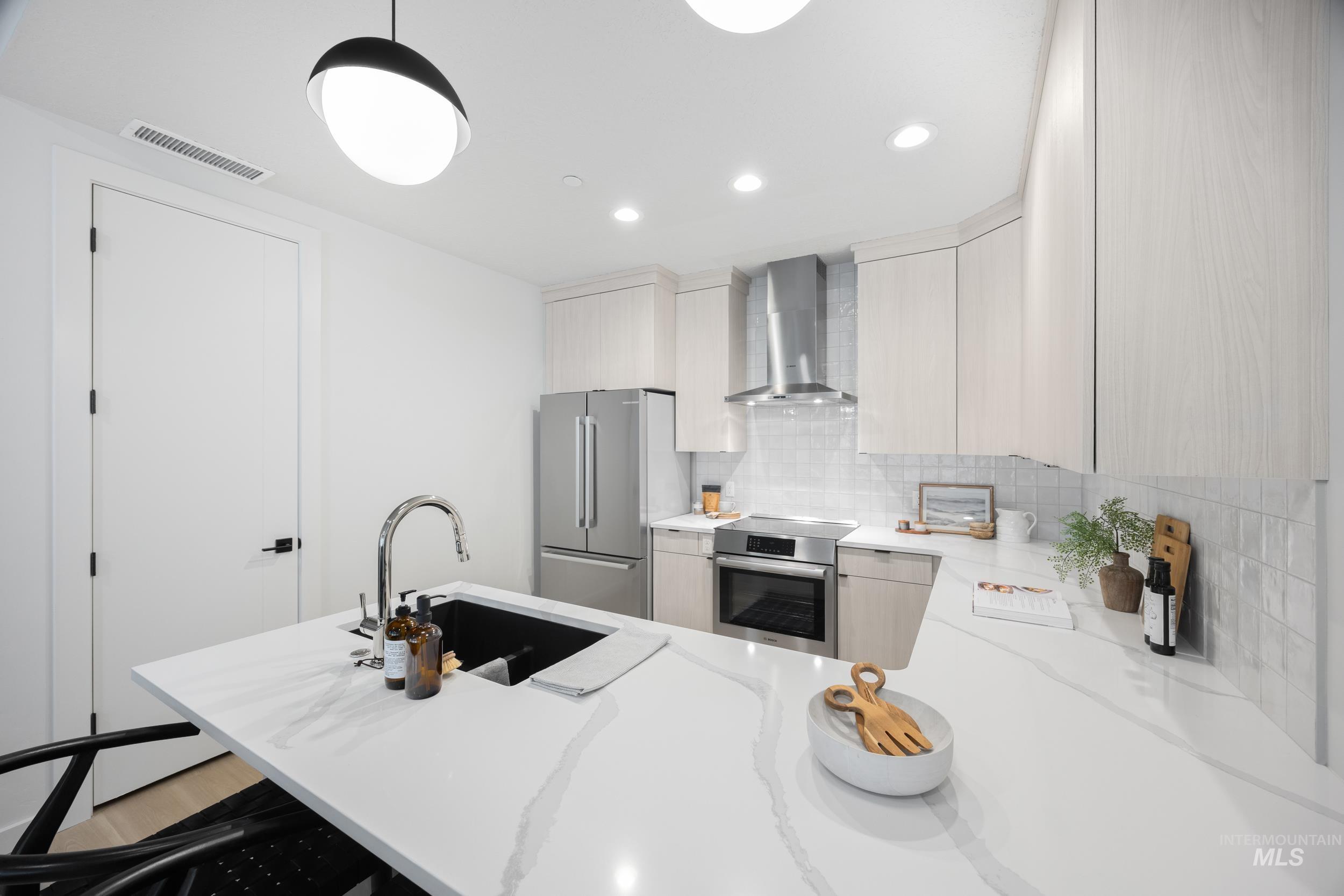 Kitchen with a kitchen breakfast bar, a peninsula, wall chimney exhaust hood, backsplash, and light stone countertops