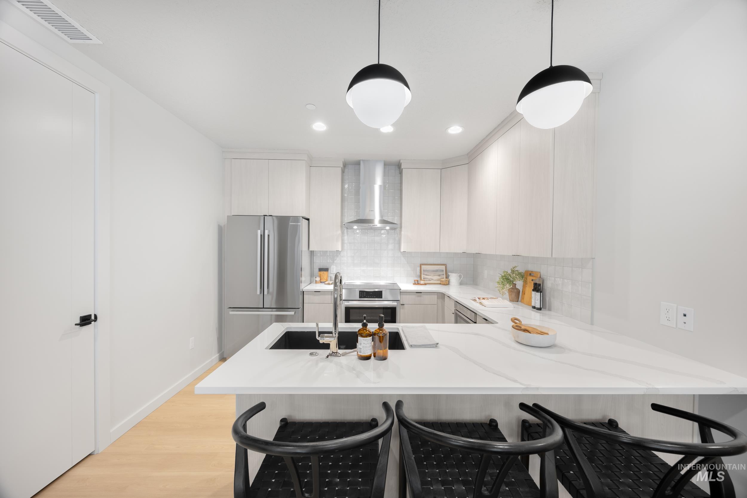 Kitchen featuring a breakfast bar, a peninsula, tasteful backsplash, stainless steel appliances, and modern cabinets