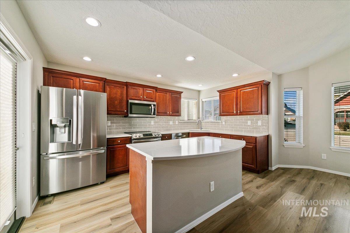 Kitchen featuring stainless steel appliances, backsplash, healthy amount of natural light, a textured ceiling, and recessed lighting