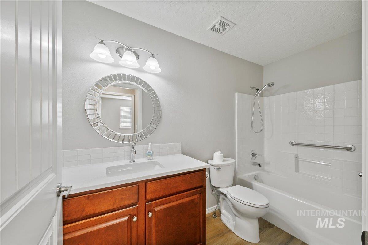Full bath featuring vanity, tub / shower combination, a textured ceiling, and light wood-type flooring