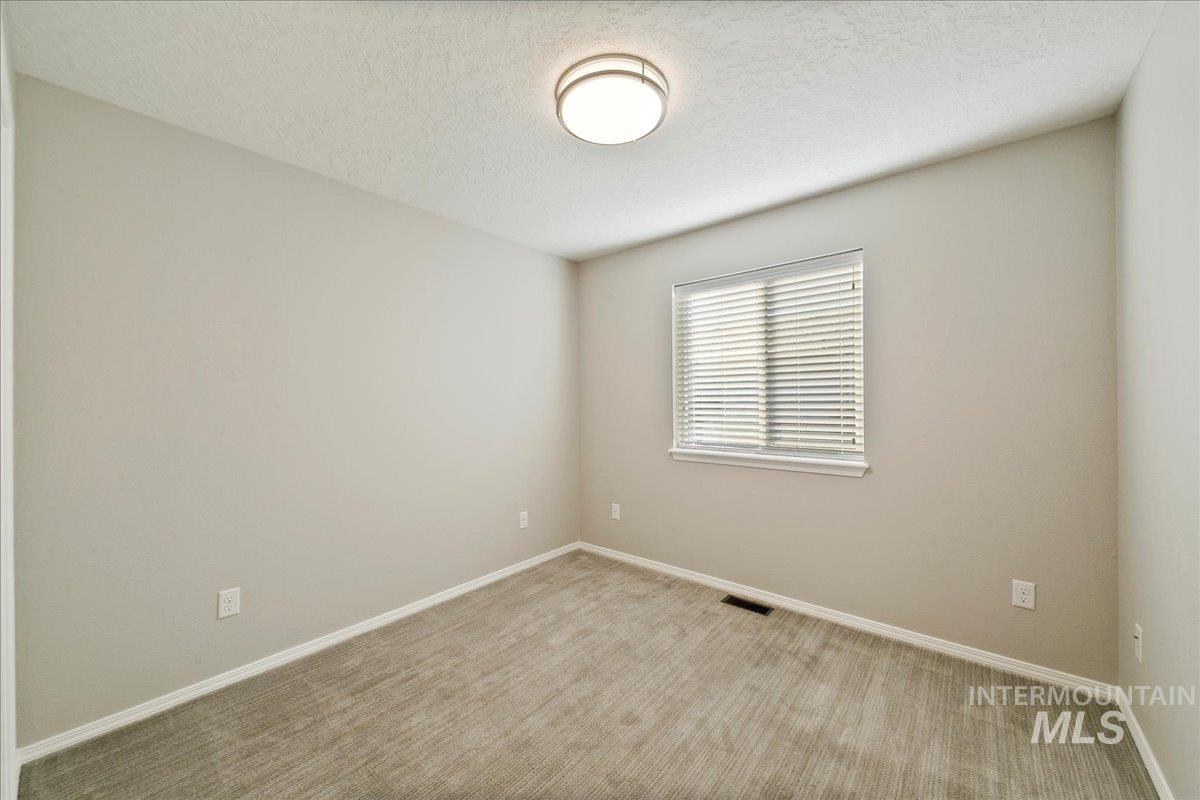 Empty room with a textured ceiling and carpet floors