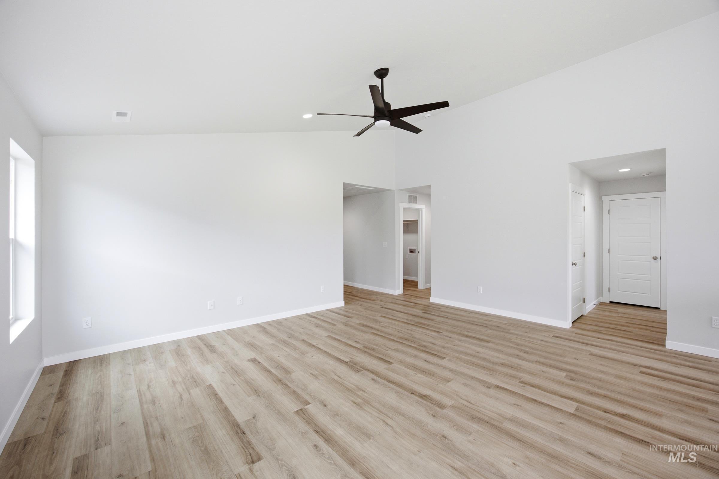 Expansive room featuring vaulted ceilings, wood-finish flooring, and a modern ceiling fan