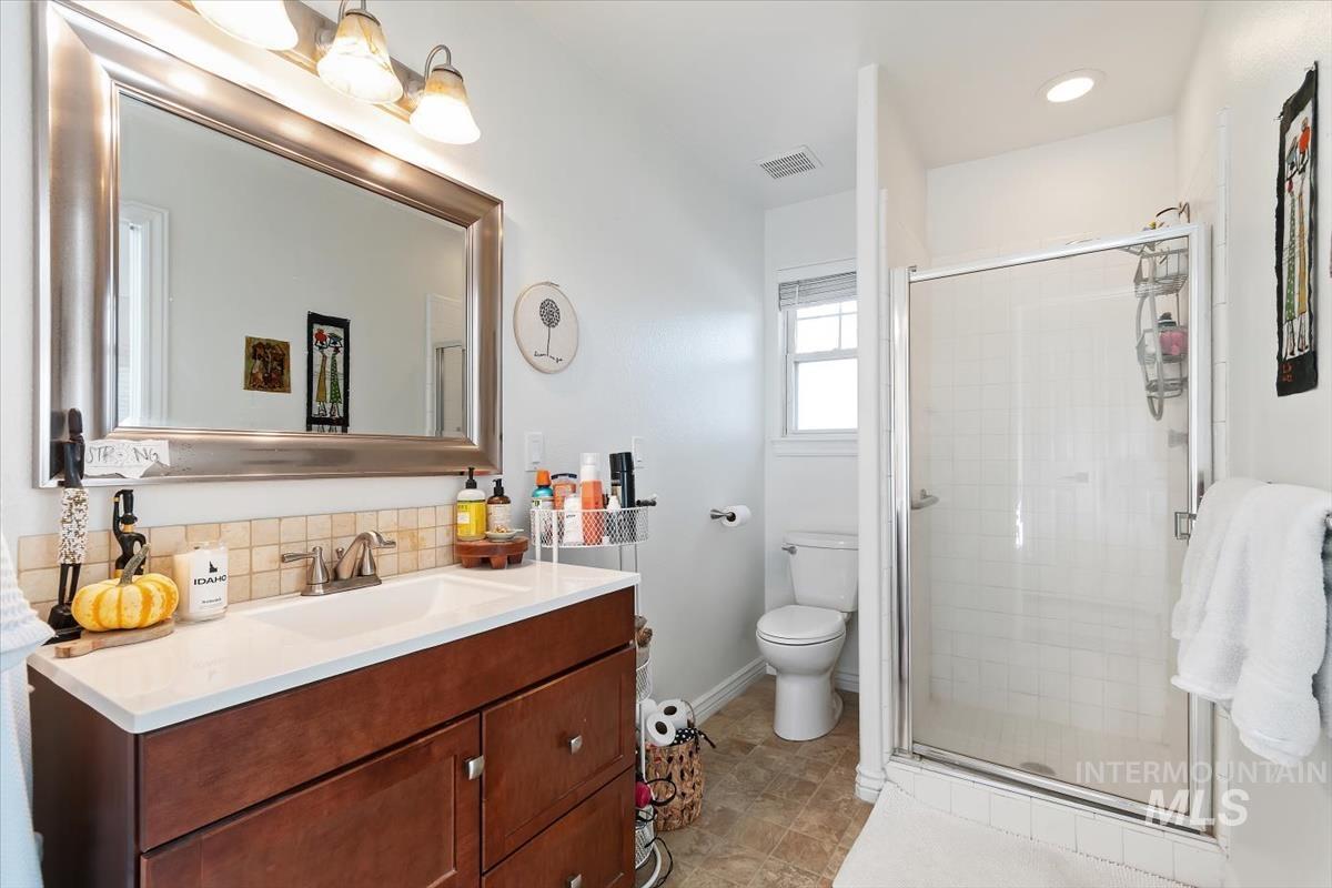 Full bathroom featuring vanity, a shower stall, decorative backsplash, and light tile patterned floors