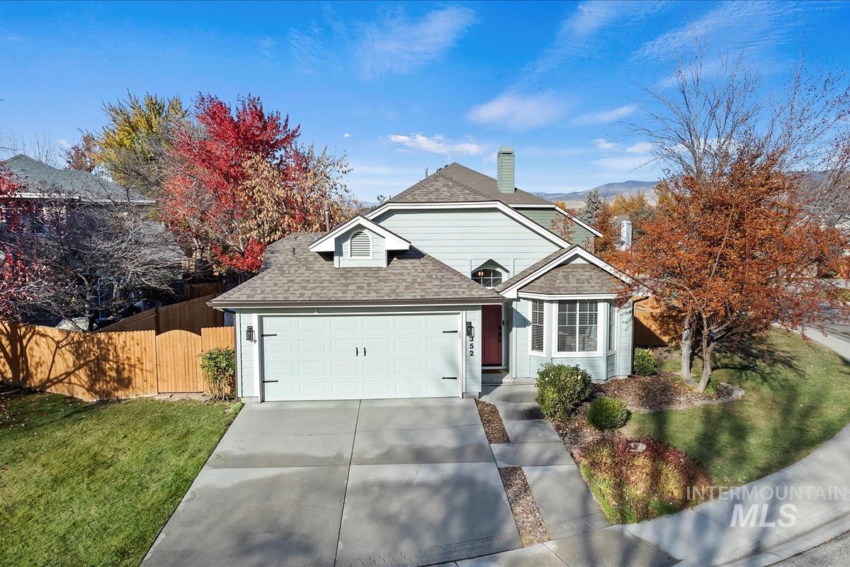 Traditional-style house featuring roof with shingles, concrete driveway, a chimney, and an attached garage