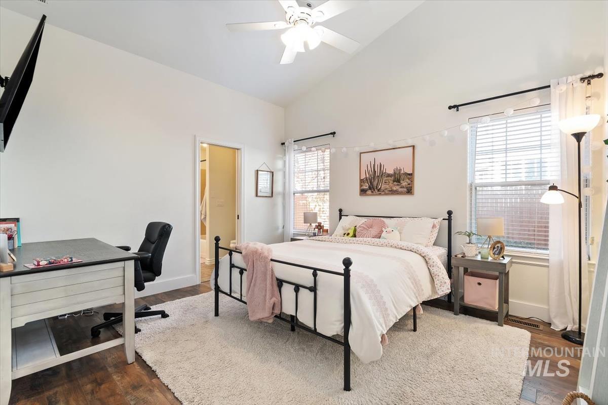 Bedroom featuring vaulted ceiling, a desk, dark wood-style floors, and a ceiling fan