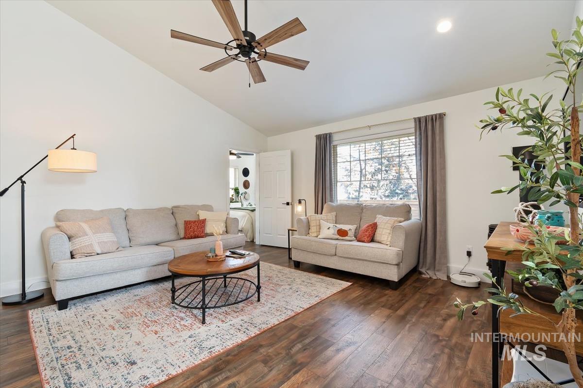 Living room with dark wood-style flooring, high vaulted ceiling, ceiling fan, and recessed lighting