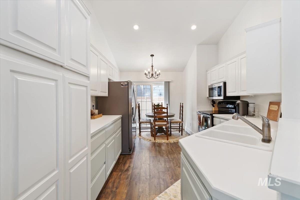 Kitchen with white cabinetry, light countertops, appliances with stainless steel finishes, a chandelier, and recessed lighting