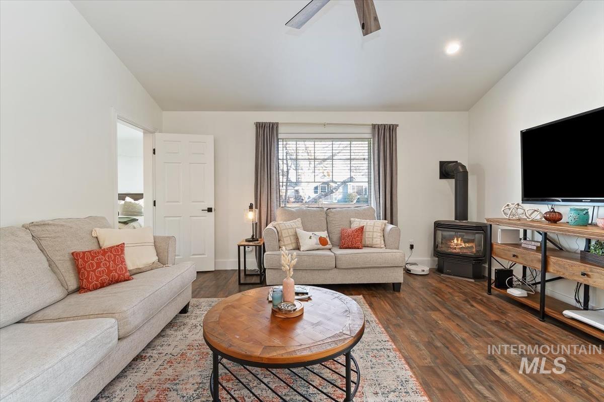Living room with a wood stove, dark wood-style floors, recessed lighting, a ceiling fan, and vaulted ceiling