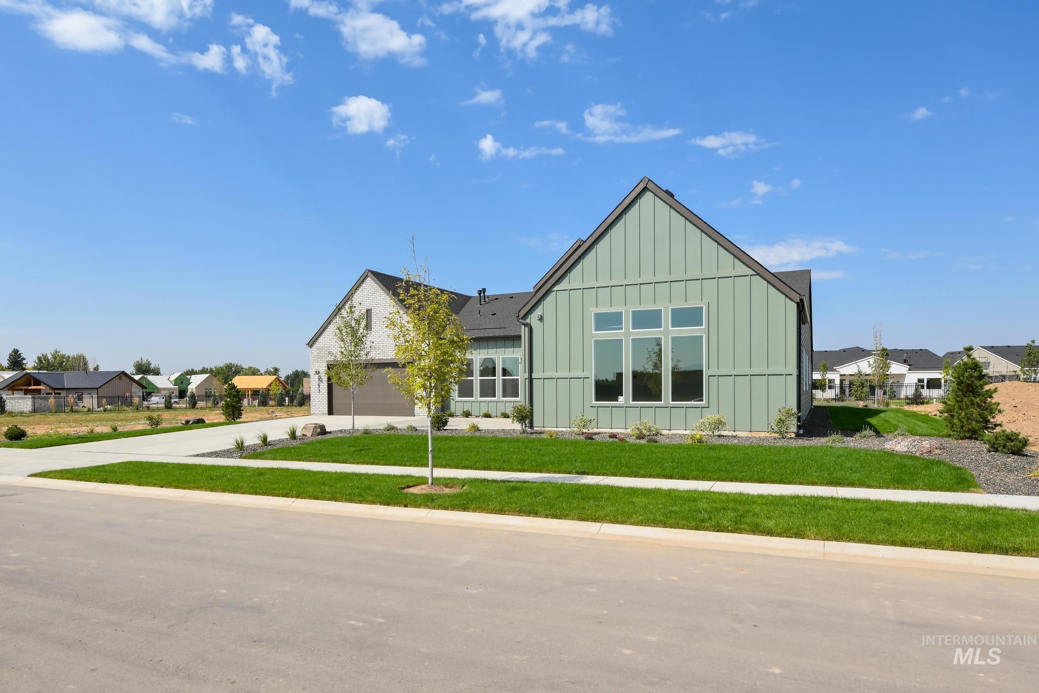 View of front facade with board and batten siding, a front yard, concrete driveway, and a garage