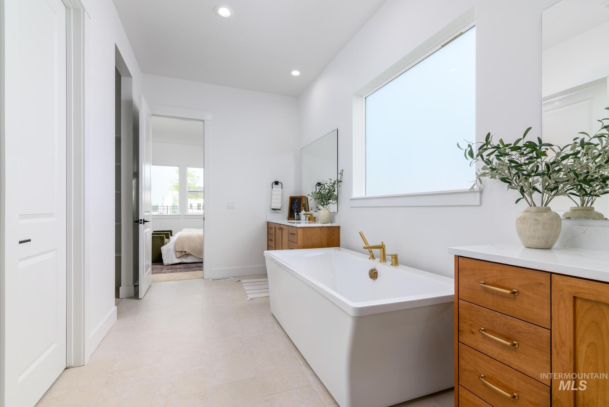Ensuite bathroom featuring a freestanding bath, vanity, and recessed lighting