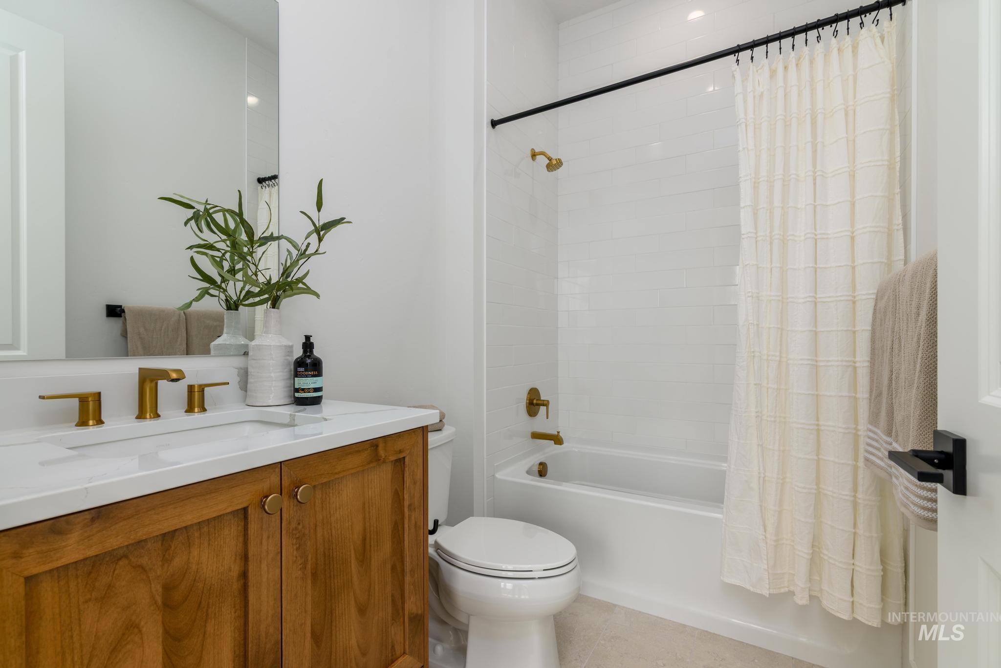 Full bath featuring shower / bath combo, vanity, and light tile patterned flooring