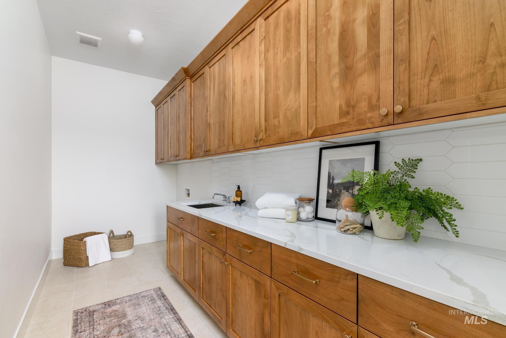 Laundry area featuring washer hookup, light tile patterned flooring, and cabinet space