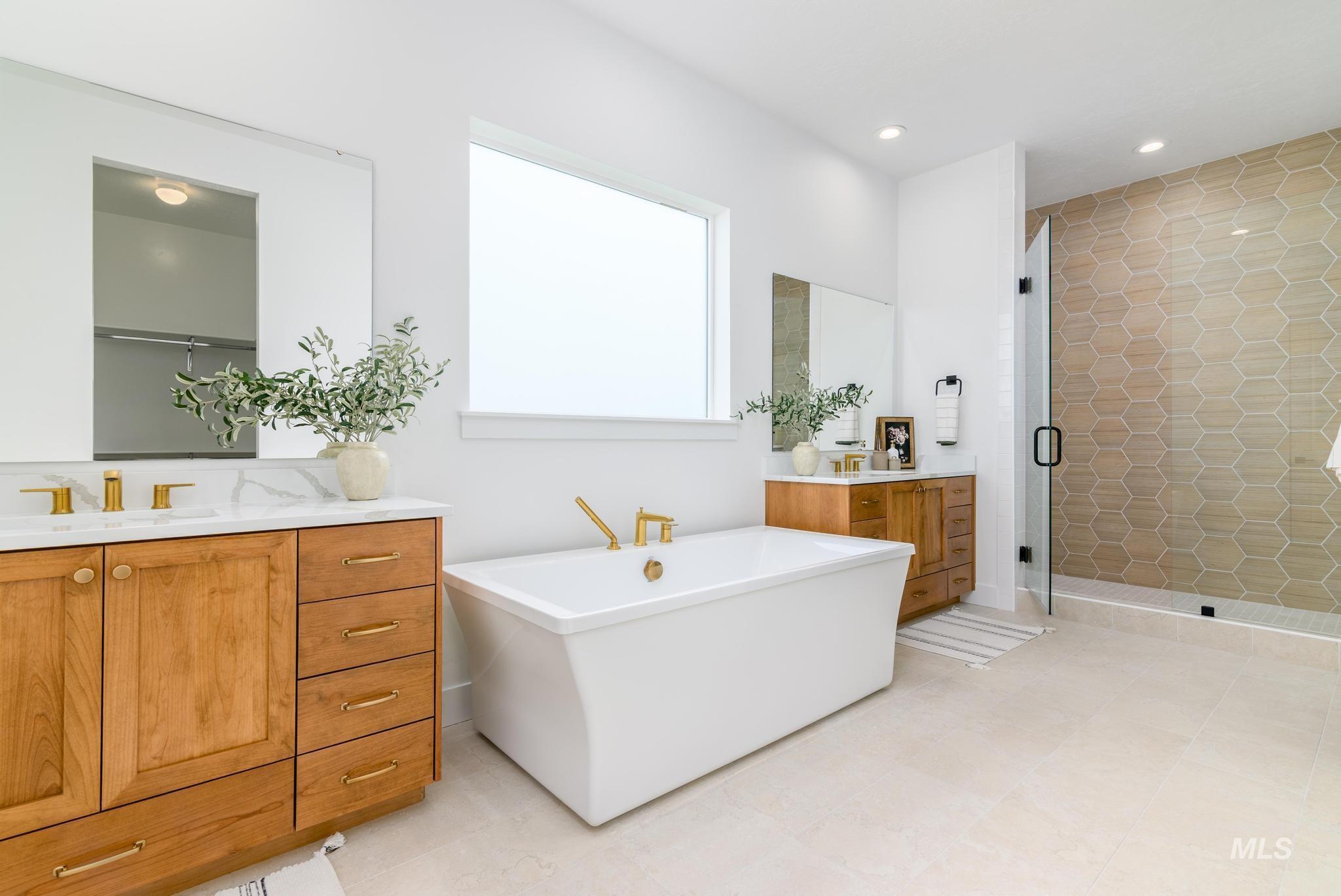 Full bath with two vanities, a shower stall, a soaking tub, and recessed lighting