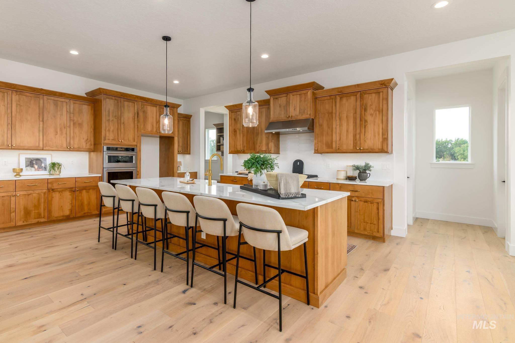 Kitchen featuring brown cabinets, a kitchen breakfast bar, recessed lighting, decorative light fixtures, and light wood finished floors