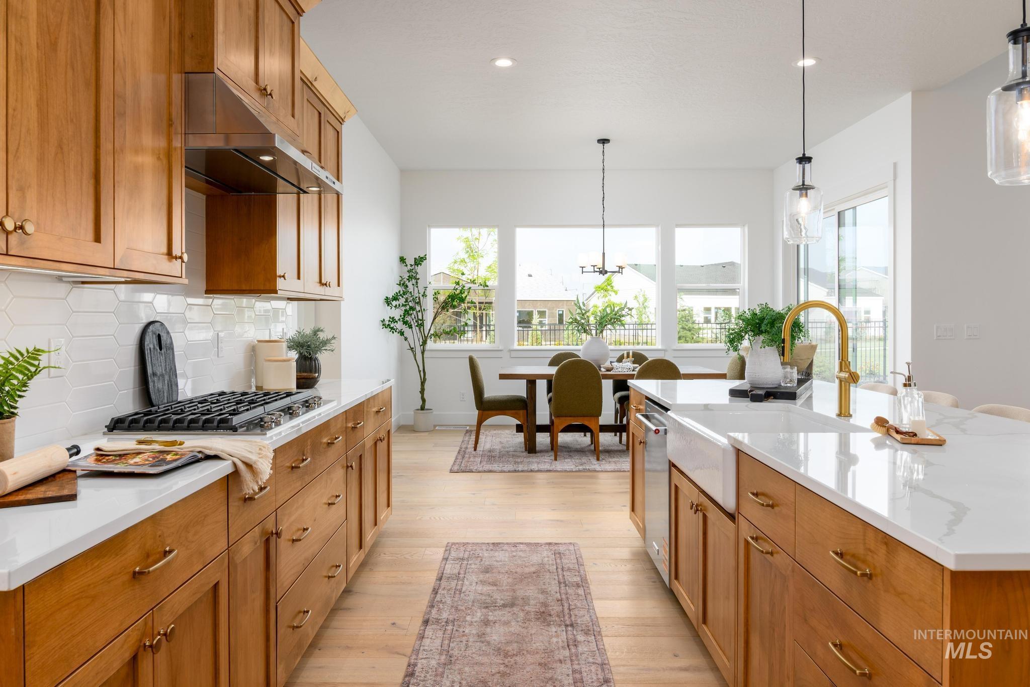 Kitchen with brown cabinetry, pendant lighting, light wood finished floors, healthy amount of natural light, and recessed lighting