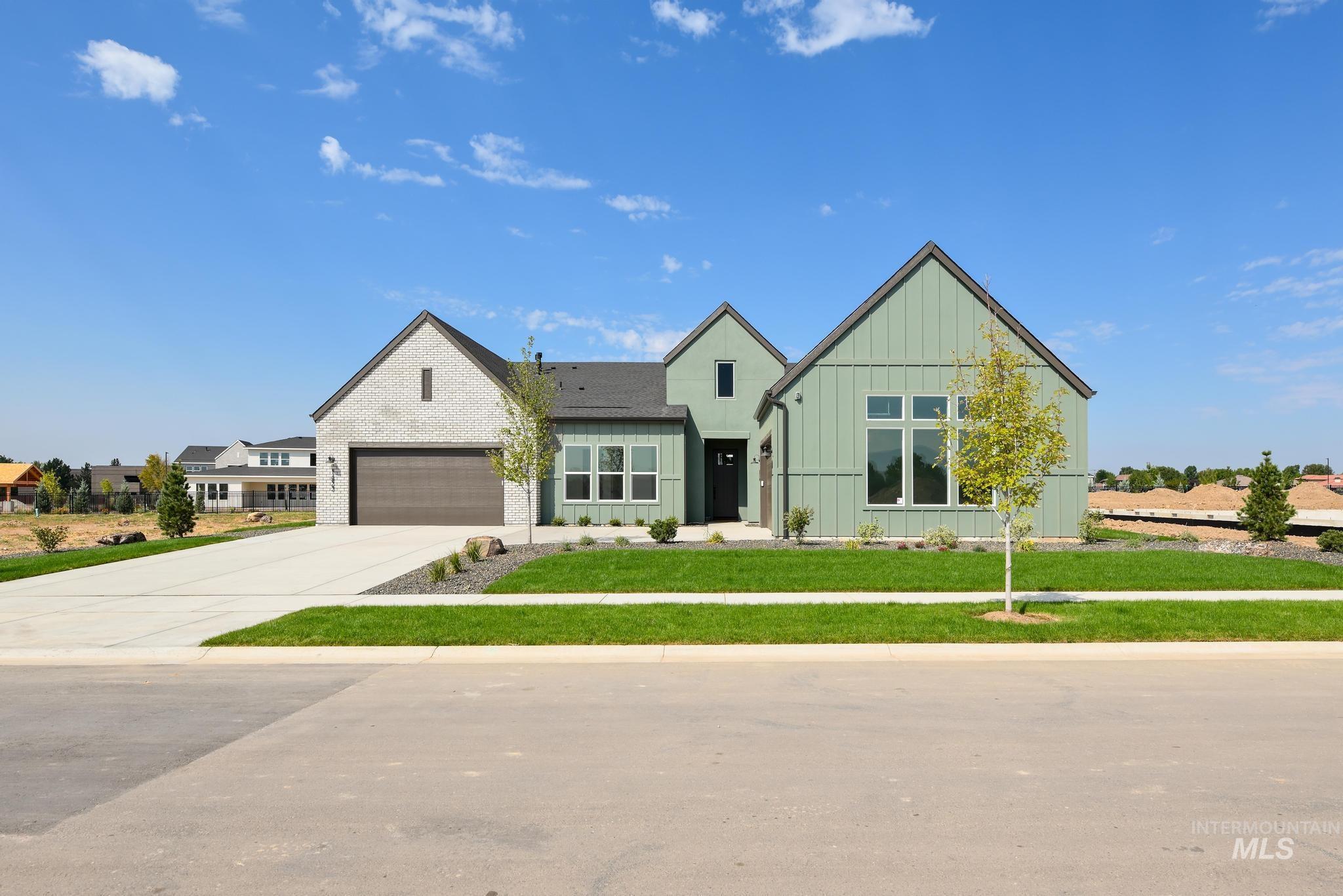 Modern inspired farmhouse with board and batten siding, concrete driveway, and a front yard