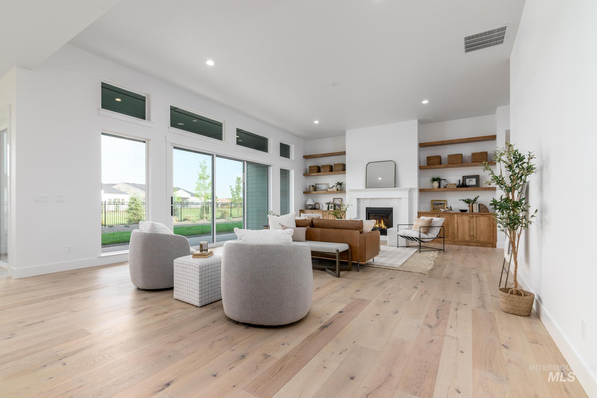 Living area with a warm lit fireplace, light wood-style floors, and recessed lighting