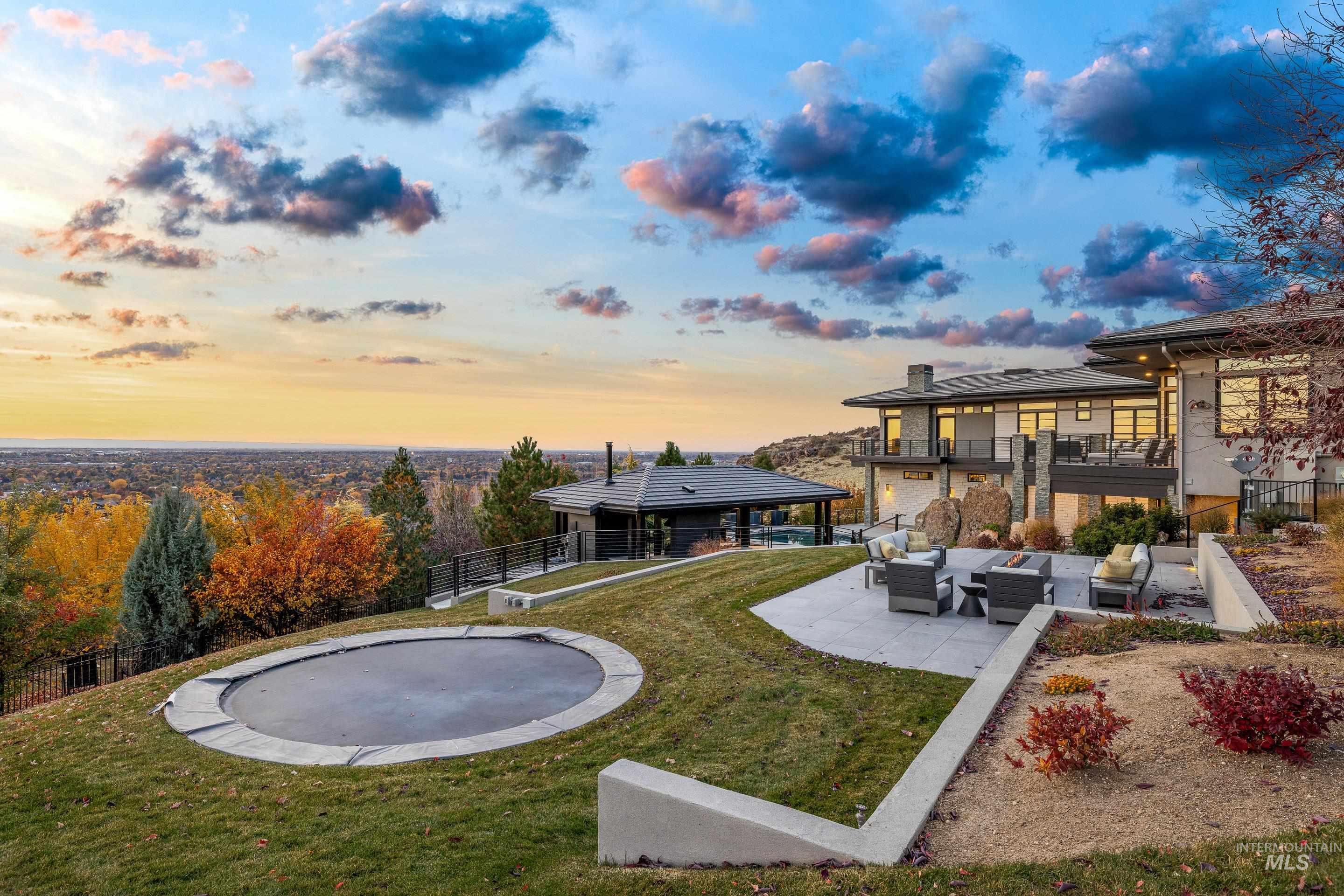 Yard at dusk with a patio area, outdoor lounge area, a fenced backyard, a trampoline, and a balcony