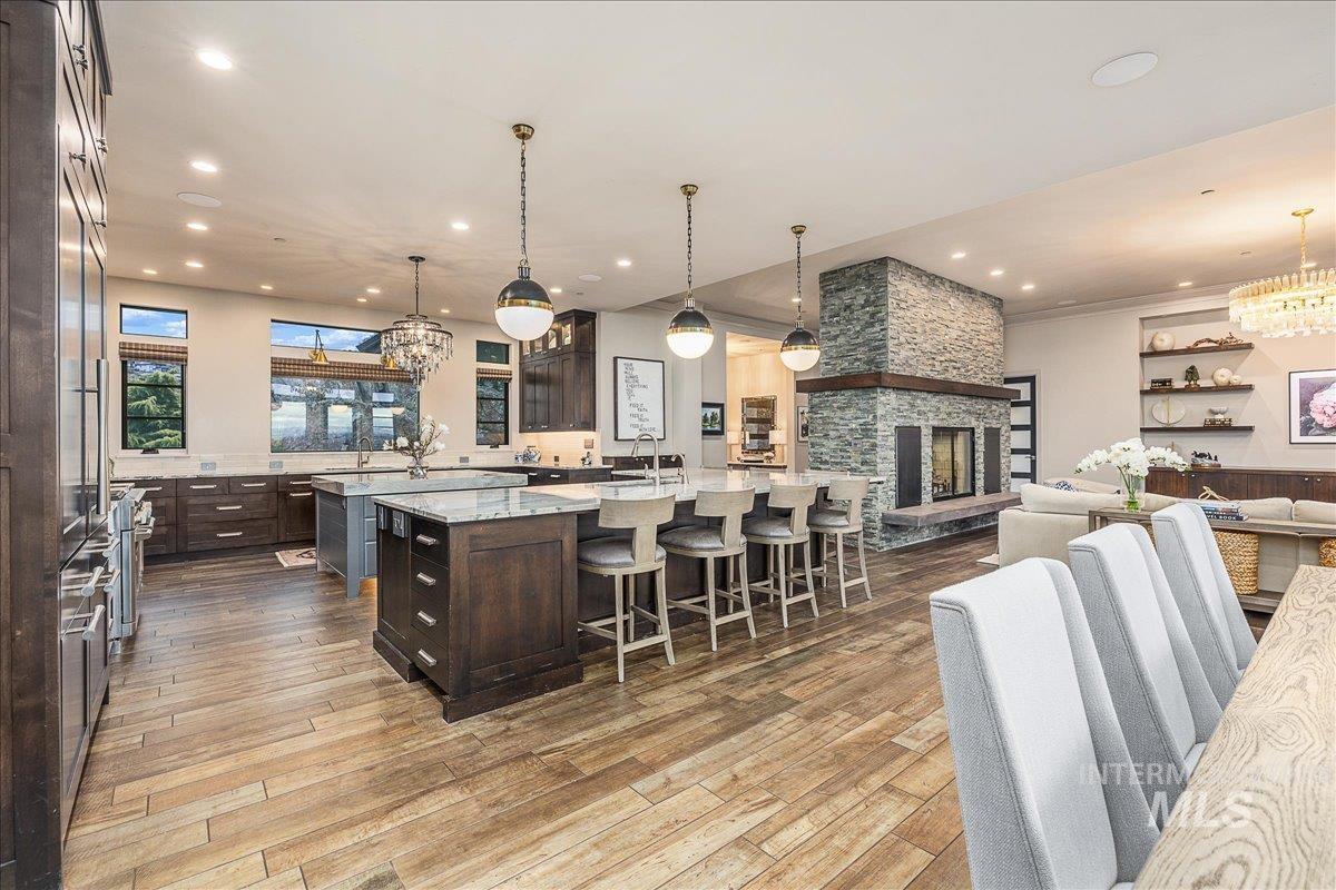 Kitchen with a chandelier, dark brown cabinets, a breakfast bar area, light stone counters, and hanging light fixtures