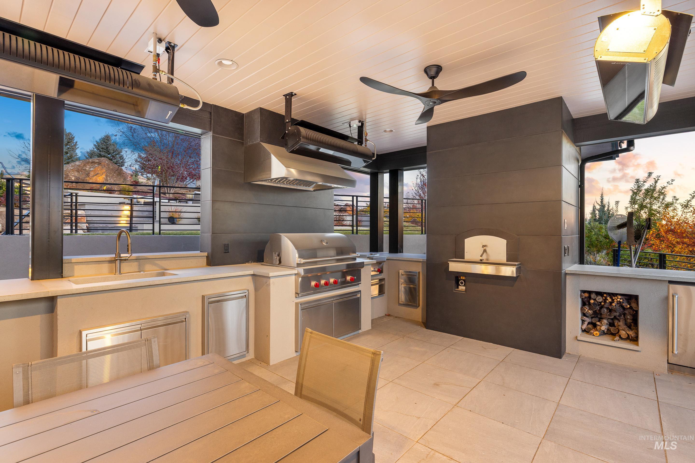 Patio terrace at dusk with exterior kitchen and a ceiling fan