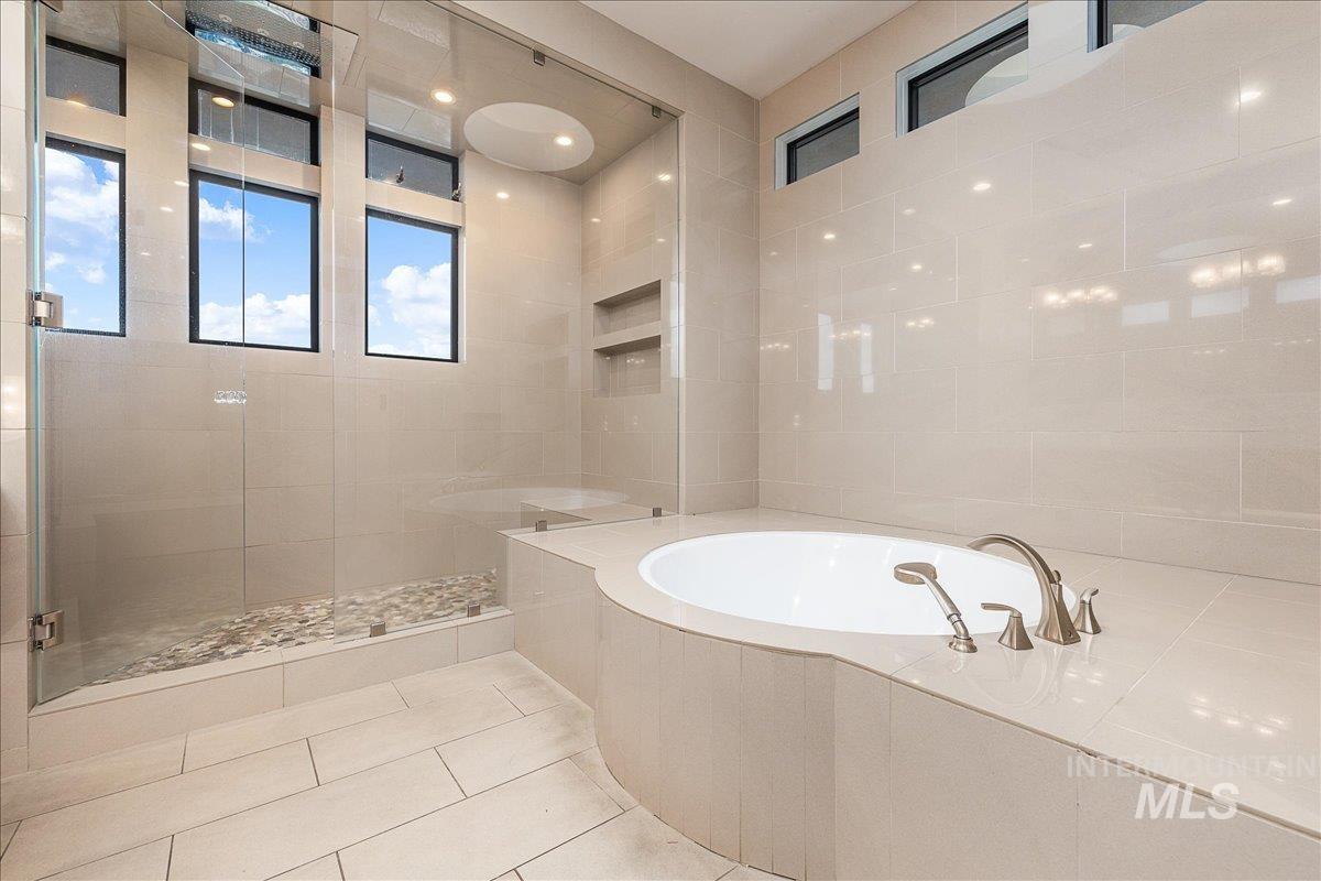 Full bathroom with a garden tub, a stall shower, tile walls, and tile patterned flooring